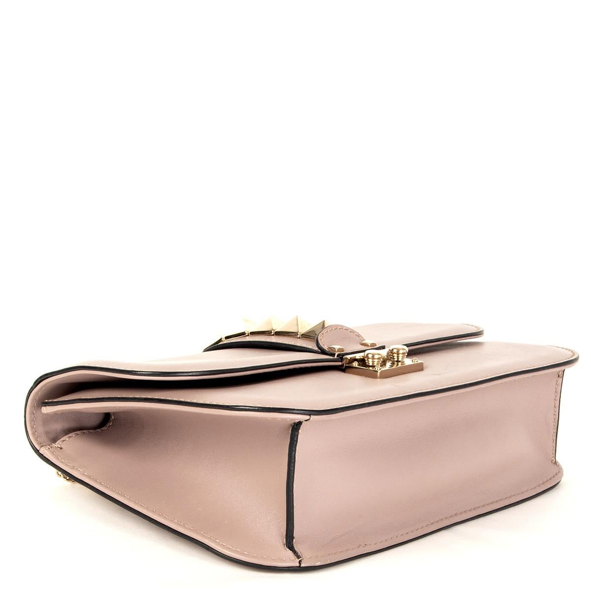 100% authentic Valentino Rockstud Glam Lock flap bag in powder rose calfskin features edgy, oversized pyramid studs in light gold-tone. A chain-link pull-through strap can be used as a shoulder strap, worn across the body, or removed to carry this
