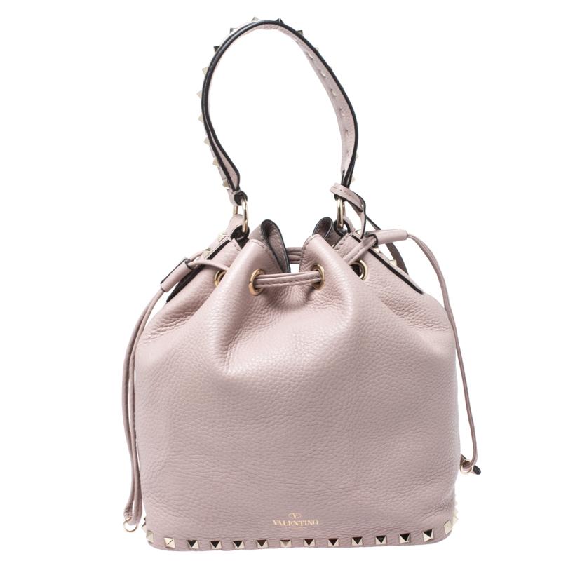 Featuring a bucket silhouette, this Valentino bag is crafted from leather and secured with a drawstring closure. It comes with a flat top handle, sits on protective base studs and comes detailed with the signature pyramid studs. It can easily hold