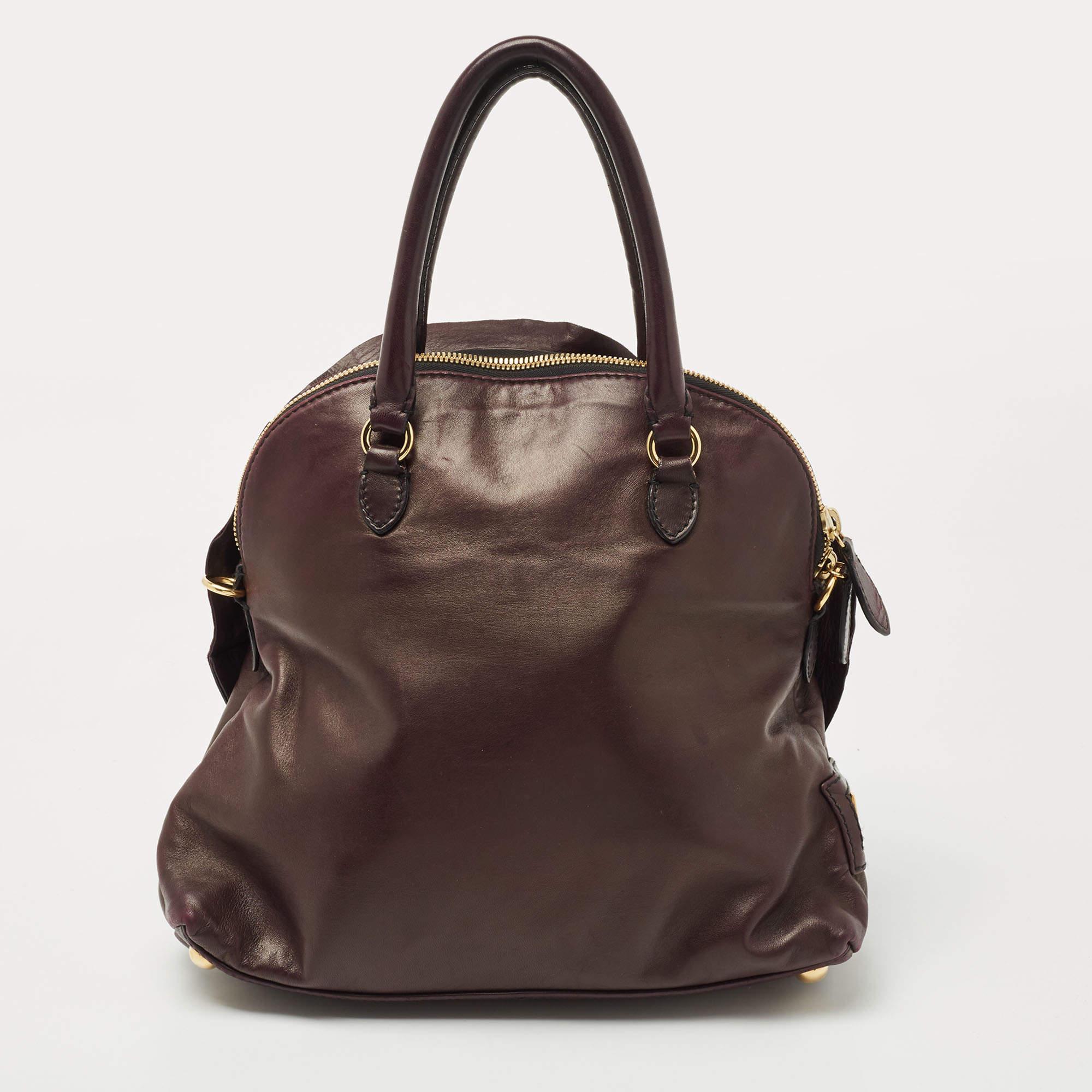 This Valentino Dome Bag is bright, classy and fabulous. Made from leather, this purple bag features the iconic Valentino rose motif pleats detailing at the front. It is equipped with protective feet and rolled handles.The zip-enclosed interior is