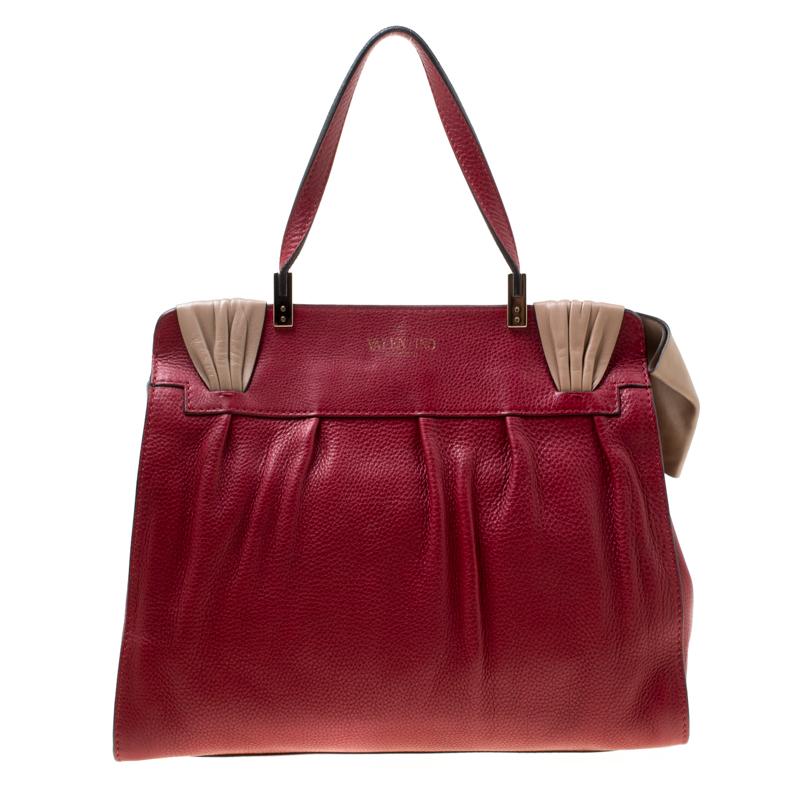 This polished and enduring Aphrodite Bow handbag by Valentino will surely meet up all your expectations. Crafted beautifully, it comes in a lovely shade of red and is accented with a notable, contrasting beige colored bow at the front. Crafted from