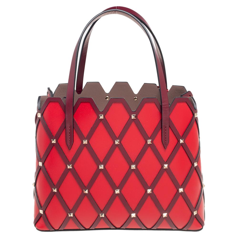 Uniquely carved into an exceptional shape and design, this Beehive tote from Valentino elevates your style flawlessly. Along with its sturdiness, this tote grants never-ending charm. It is made from red-burgundy leather and features gold-toned