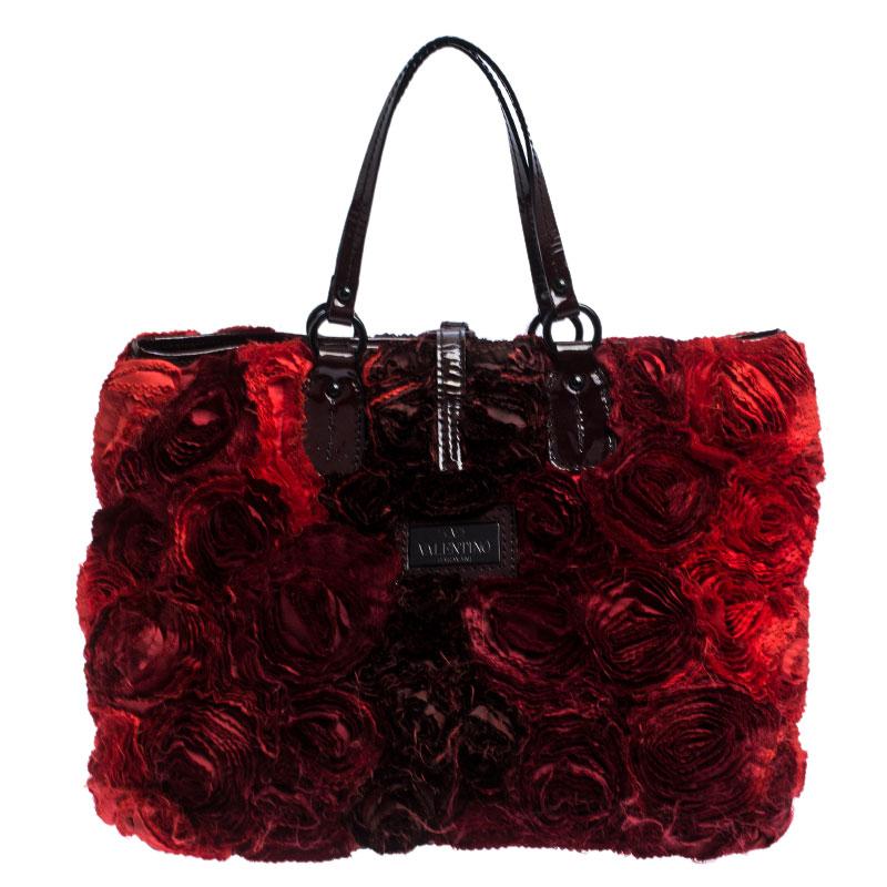 Valentino is known to bring out unique and one of a kind pieces year after year and this bag is indeed one of them! It is crafted from red leather and features an artistic silhouette. It flaunts a flower applique detailing all over and a black-tone