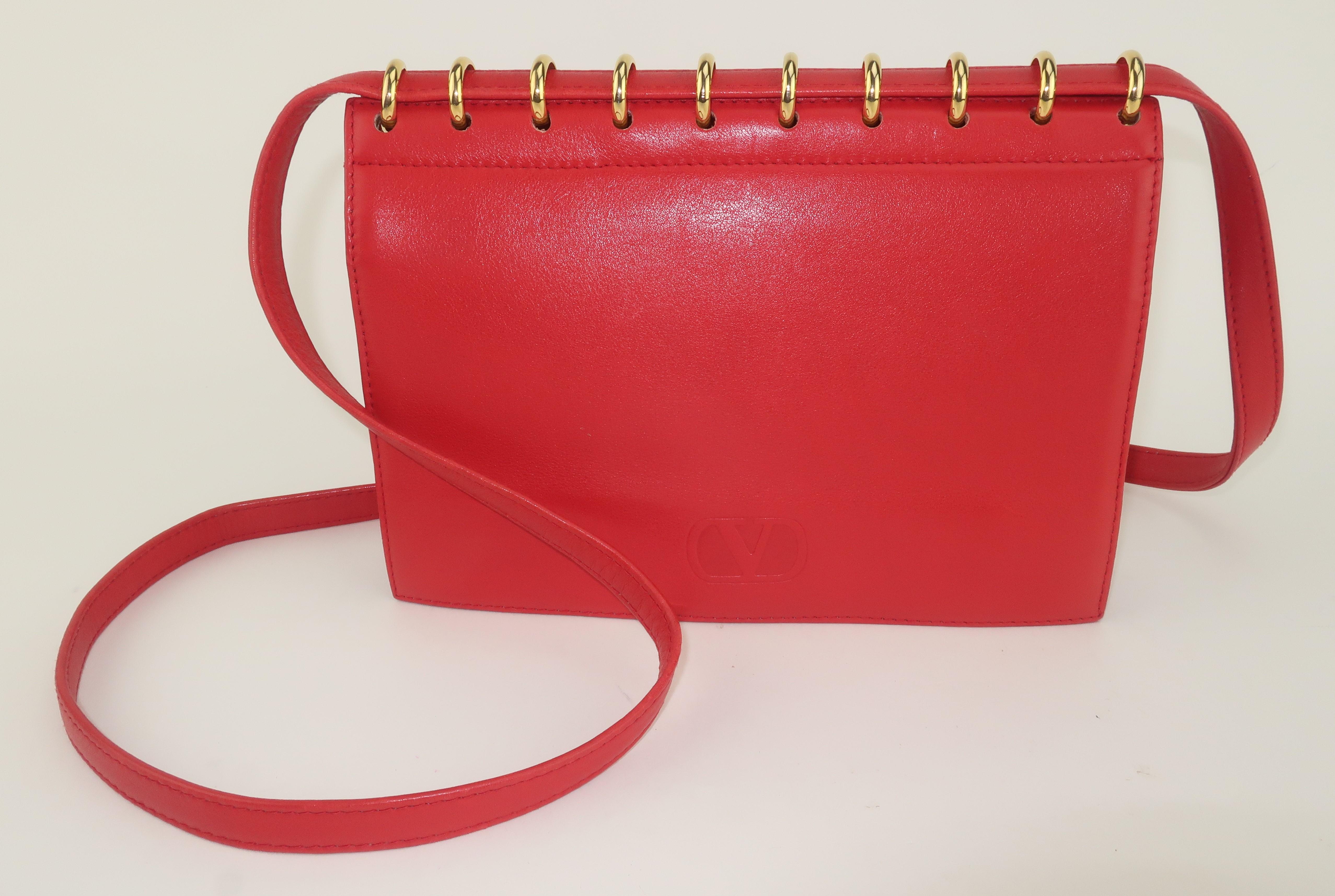 1980’s Valentino Garavani red leather handbag with shoulder strap and unique gold spiral hardware.  The bag is subtly embossed with ‘V’ logo on the front flap which features a double snap closure.  It opens to reveal a leather lined interior which