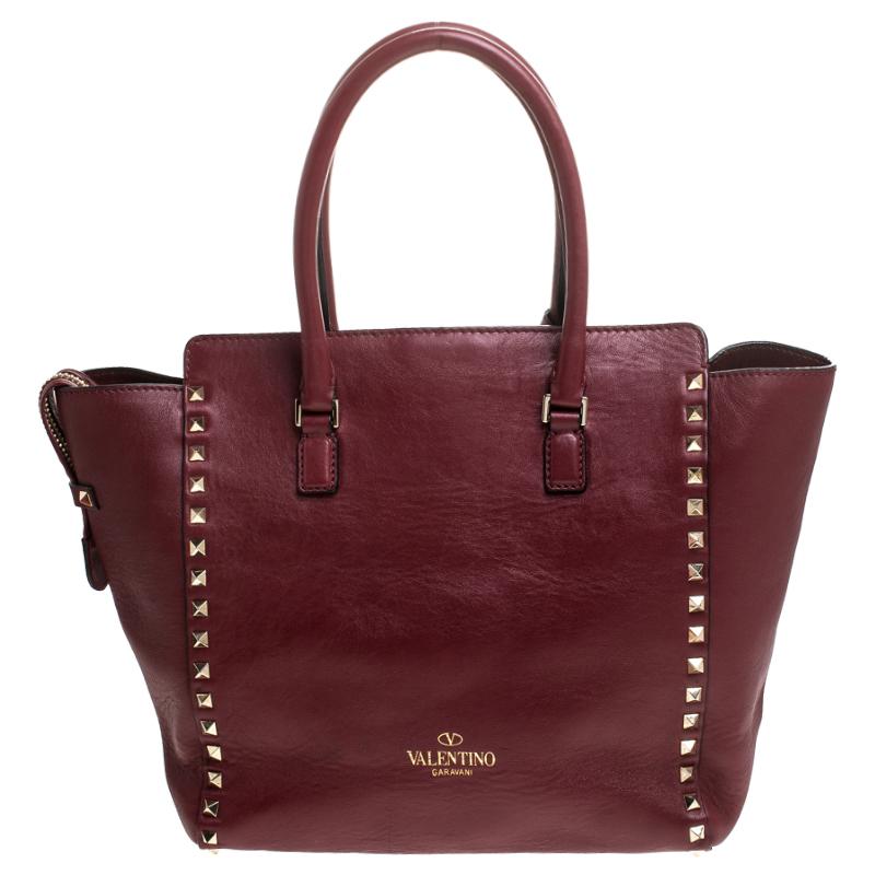 Valentino brings you this super-stylish tote that carries a design which will surely grab the attention of your onlookers. It has a classy red exterior decorated with the signature pyramid Rockstuds. The leather tote is complete with a spacious