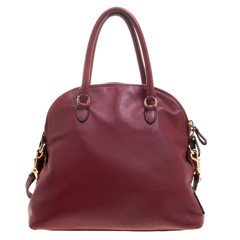 Satchels like these are hard to come by, so quickly grab one when you can! Crafted from red leather this dome satchel by Valentino features a beautiful rose detailing on the front. Equipped with dual top handles, a detachable shoulder strap,