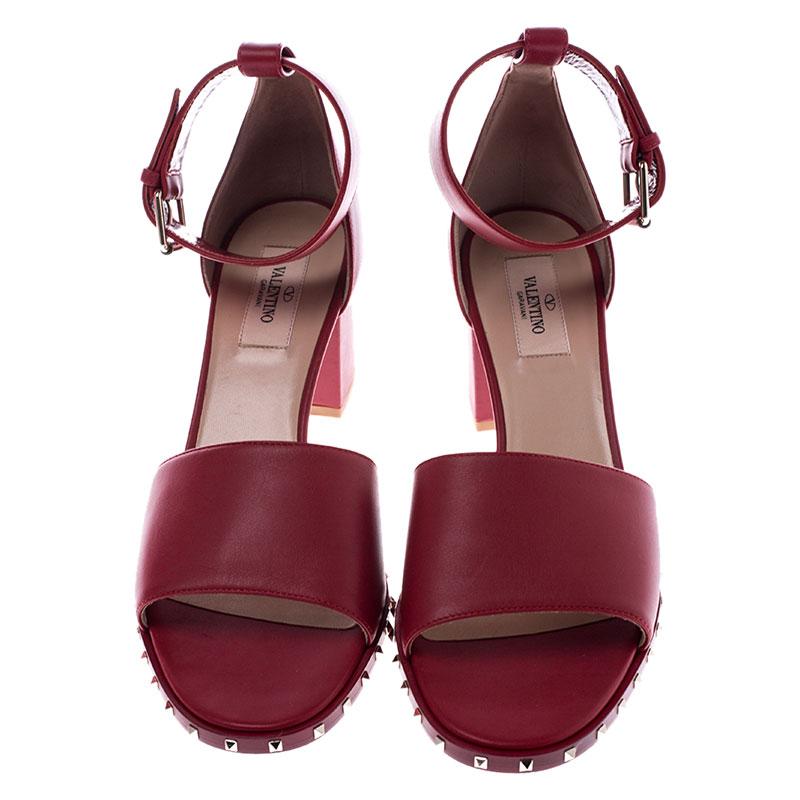 This lovely pair of Valentino sandals has a stylish silhouette and simple design. These block heel sandals have been crafted from red leather and feature adjustable ankle straps and the signature Rockstuds outlining the platforms. Complete with open