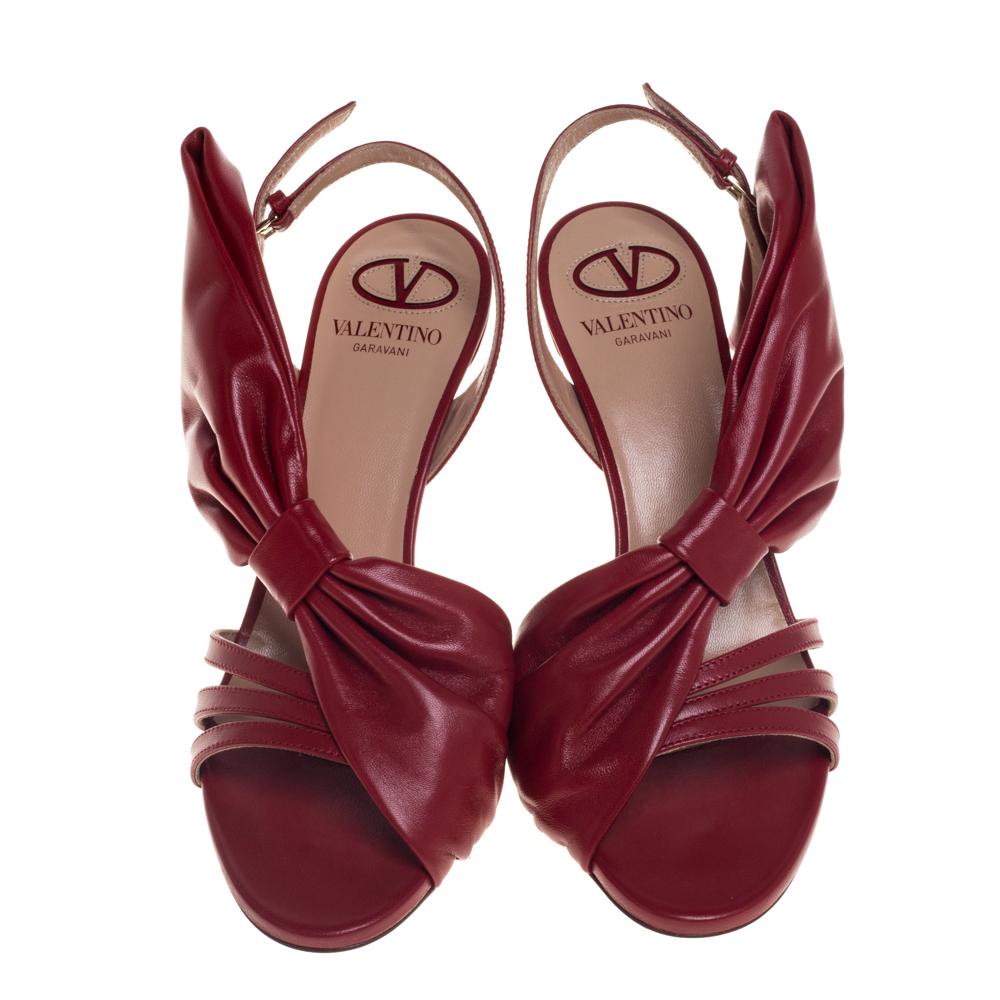 Crafted in Italy, these Valentino sandals are nothing less than gorgeous! They are made from leather in a red hue then adorned with oversized bows on the sides. The uppers are accented with slender straps and secured with slingbacks.

Includes: Info