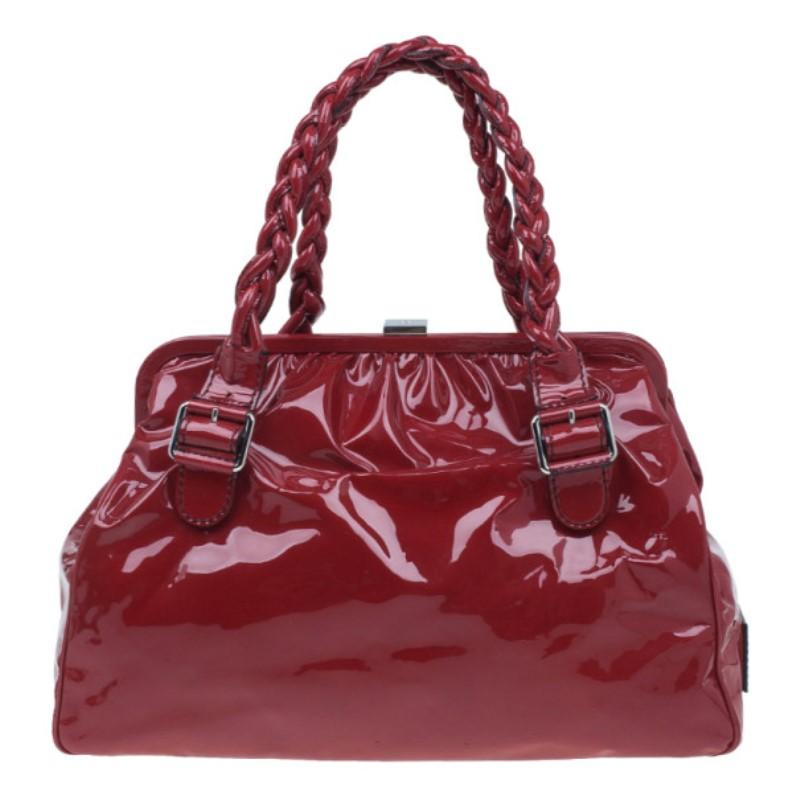 This Valentino bag from the Histoire collection is designed with a historic aesthetic reminding us of museums. Made from patent leather in a red shade, it features double top braided leather handles with gunmetal buckles, two front flap pockets, and