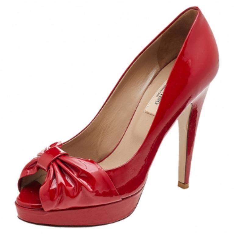 Exude poise and perfection as you walk in these pumps from the House of Valentino. They are crafted using red patent leather on the exterior, with a bow motif attached to the peep-toes. They are raised on 12 cm heels. Make a stunning style statement