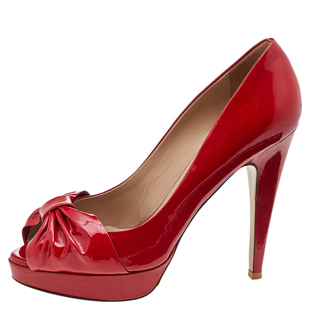 Exude poise and perfection as you walk in these pumps from the House of Valentino. They are crafted using red patent leather on the exterior, with a bow motif attached to the peep-toes. They are raised on 12 cm heels. Make a stunning style statement