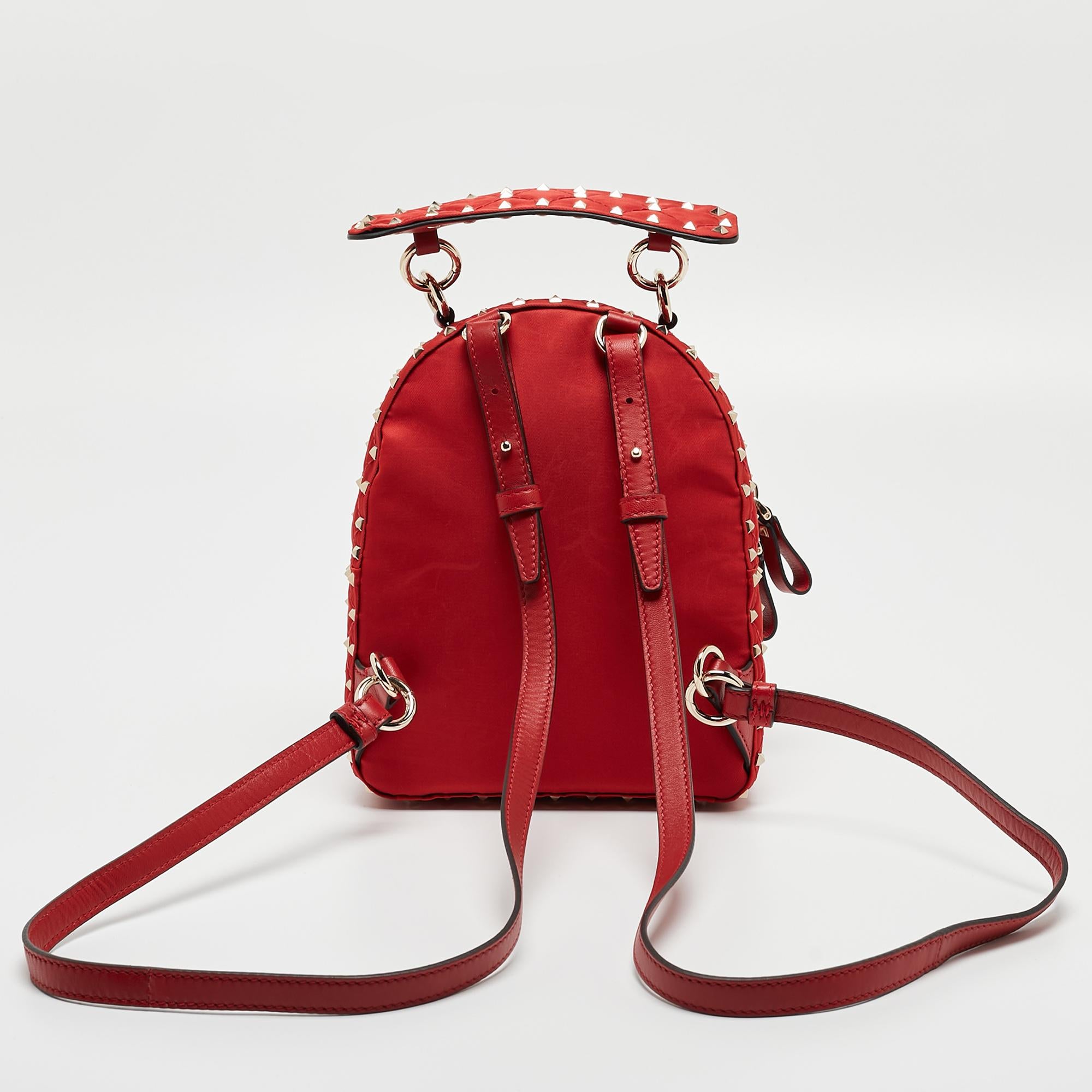 Ditch those regular totes for this chic Valentino backpack. Decorated with the iconic Rockstuds and a quilted design all over, this red backpack features a main zipper compartment along with an exterior zip pocket. It comes with a top handle and