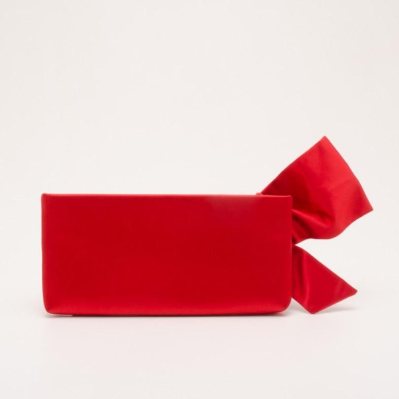 Bold, yet feminine, this Red Satin Pleated Bow Clutch by Valentino is what you want to carry on an evening out. The red satin exterior is simply detailed with a lovely over-sized bow and a top zip closure. Its open interior is also lined with red