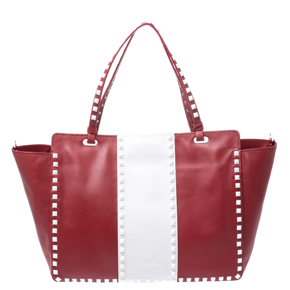 This iconic tote from Valentino has been spotted in the arms of many celebrities and models. Crafted in Italy, it has been made from quality leather and flaunts navy red and white hues. It features a lovely silhouette, signature Rockstud detailing