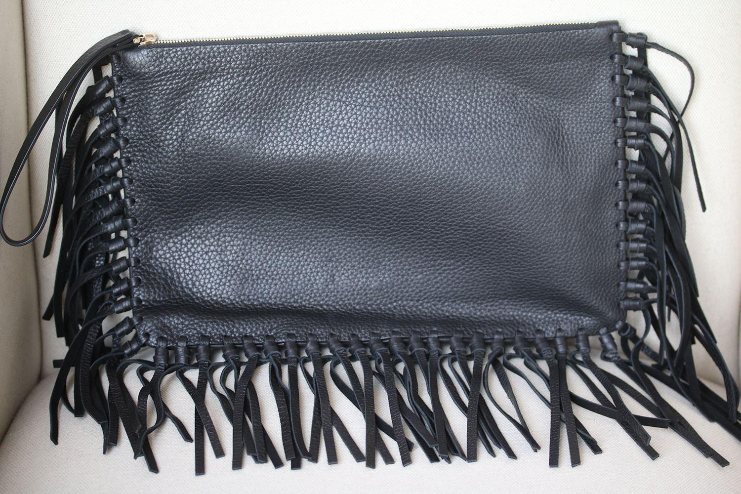 Grained leather with suede lining and gold-tone hardware. Zip top closure. Interior zip pocket and pockets. Fringe trim. Made in Italy.

Dimensions: Approx. 13.5 x 16 x 1 inches

Condition: As new condition, no sign of wear. 