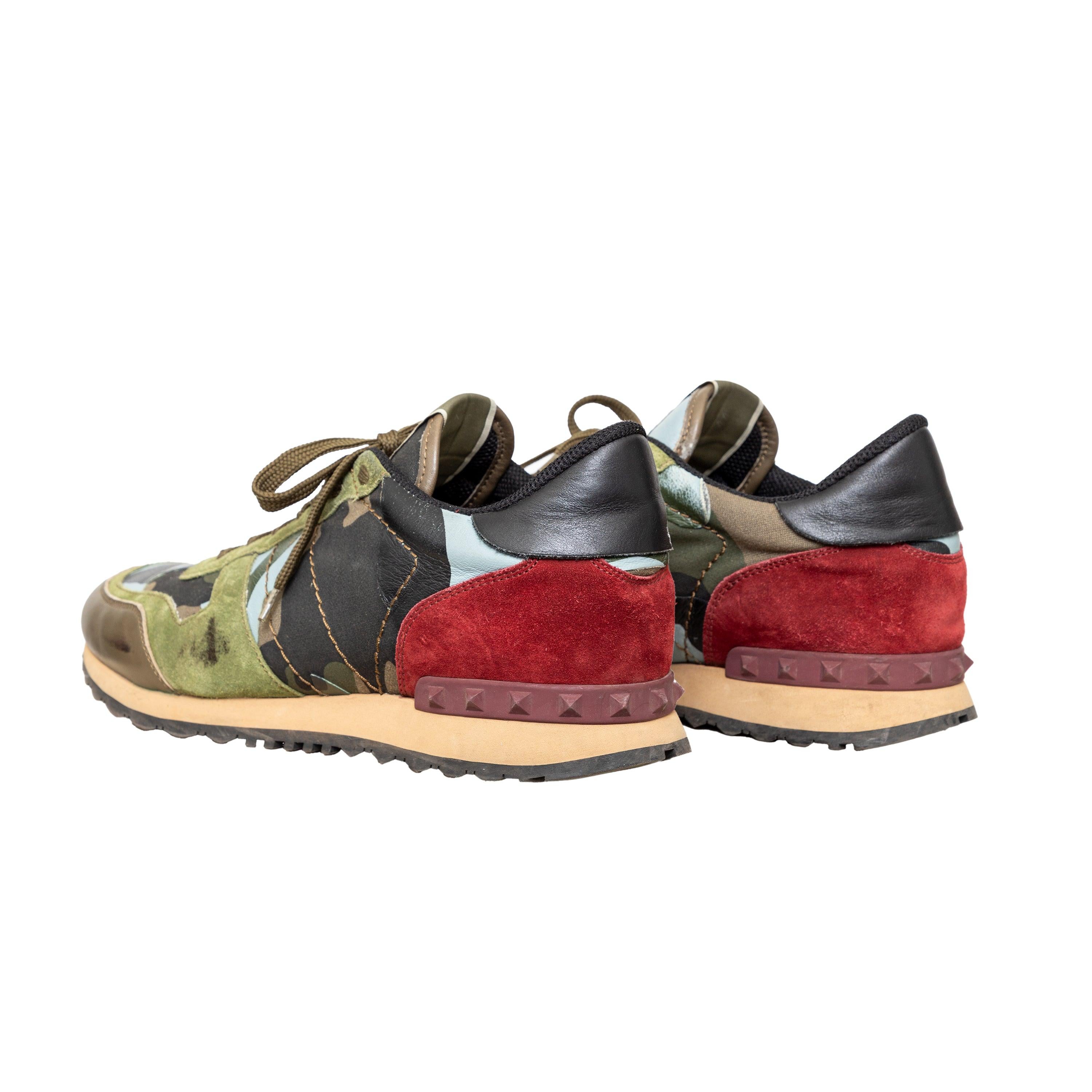 Le sneakers Rockrunner di Valentino sono realizzate in pelle scamosciata, tela e pelle con un design mimetico e accenti rossi sul retro. Caratterizzata da dettagli con borchie per un look inconfondibile.
 Osservazioni: Ci sono alcuni graffi e