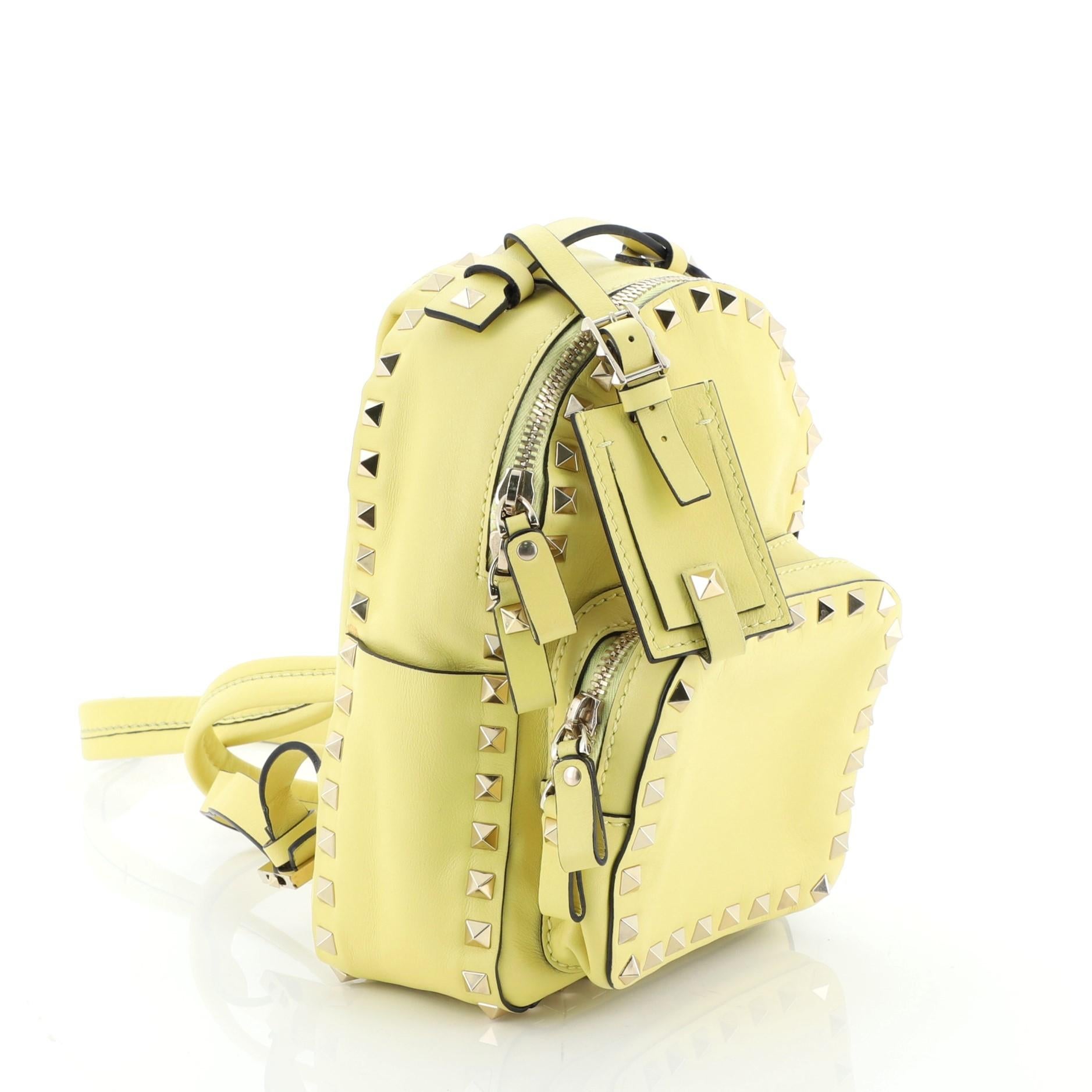 This Valentino Rockstud Backpack Leather Mini, crafted in yellow leather, features adjustable backpack straps, exterior front zip pocket, rockstud detailing and gold-tone hardware. Its zip closure opens to a neutral fabric interior. 

Estimated
