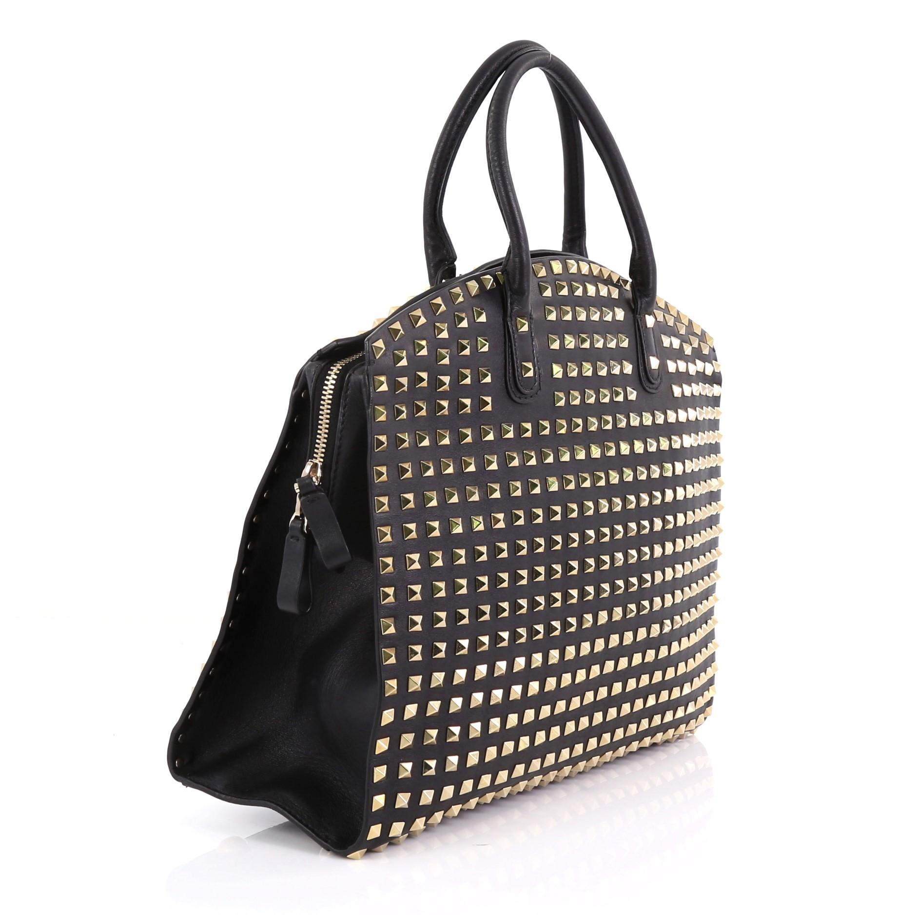 This Valentino Rockstud Convertible Dome Tote Full Studded Leather, crafted in black leather, features dual rolled top handles, pyramid stud details, and gold-tone hardware. Its zip closure opens to a black fabric interior with zip and slip pockets.