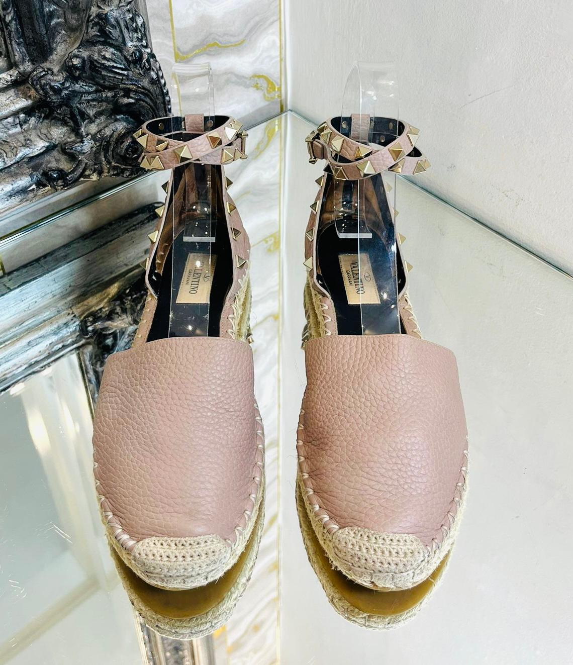 Valentino Rockstud Double Leather Espadrilles

Nude sandals crafted from textured leather and set on a jute platform.

Detailed with the brand's signature hand-placed gold pyramid studs.

Featuring double ankle strap with buckle closure and white