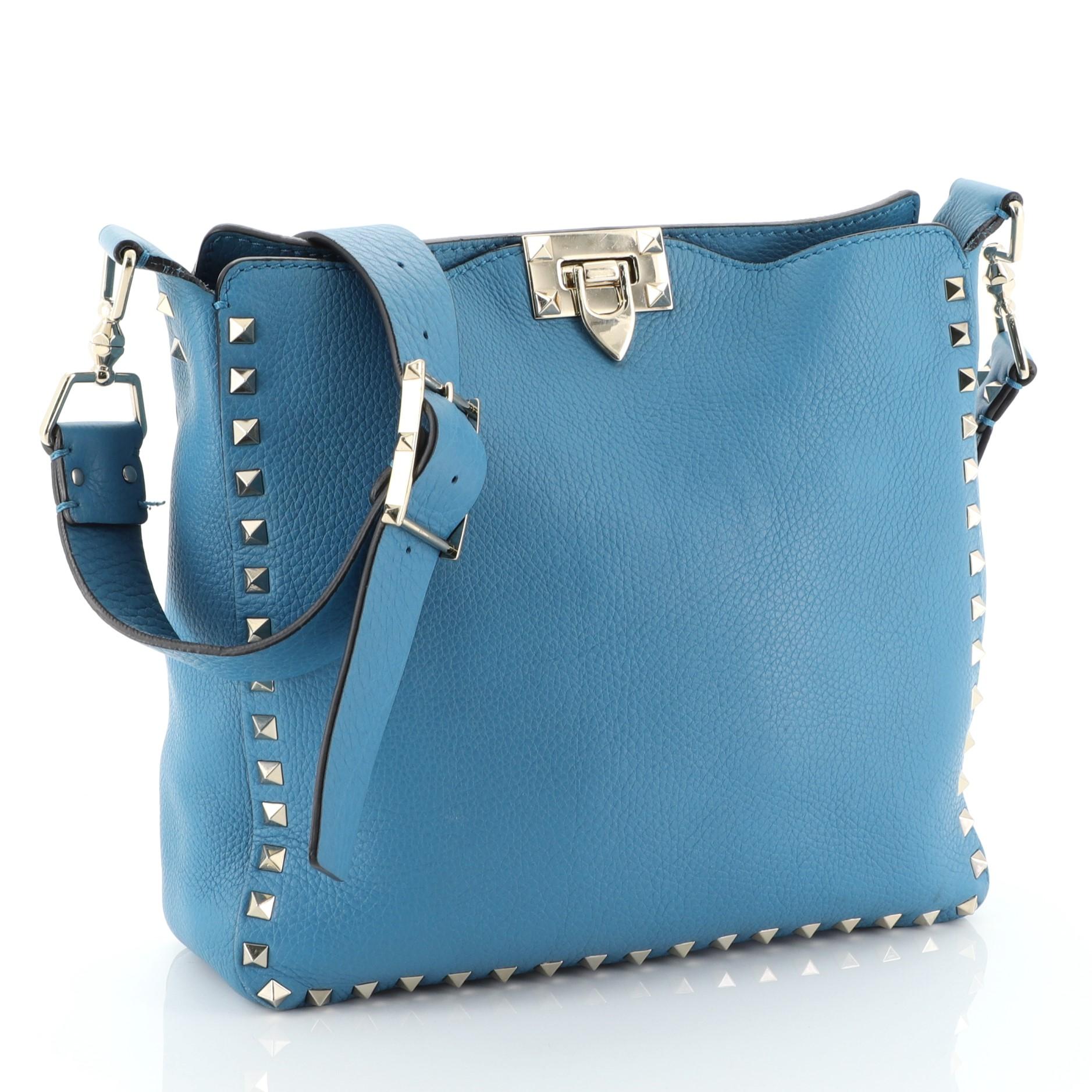This Valentino Rockstud Flip Lock Messenger Bag Leather Small, crafted in blue leather, features an adjustable cross-body strap, pyramid studs detailing, stamped logo and gold-tone hardware. Its flip-lock closure opens to a blue suede interior with