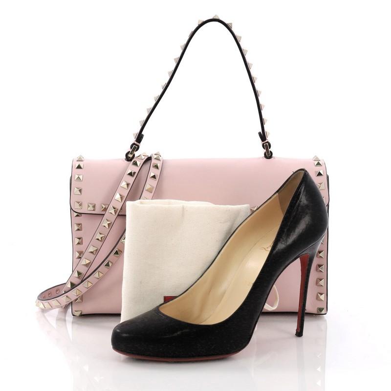 This Valentino Rockstud Flip Lock Top Handle Bag Leather Small, crafted from pink leather, features a leather top handle with stud detailing, rockstud trims, and gold-tone hardware. Its flip-lock closure opens to a beige fabric interior with a