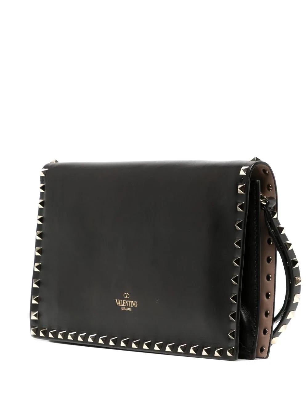 The Valentino Rockstud Leather Clutch Bag is a stunning and versatile accessory that combines edgy style with timeless elegance effortlessly. The bag features Valentino's iconic pyramid-shaped Rockstuds, meticulously applied along the edges. The bag