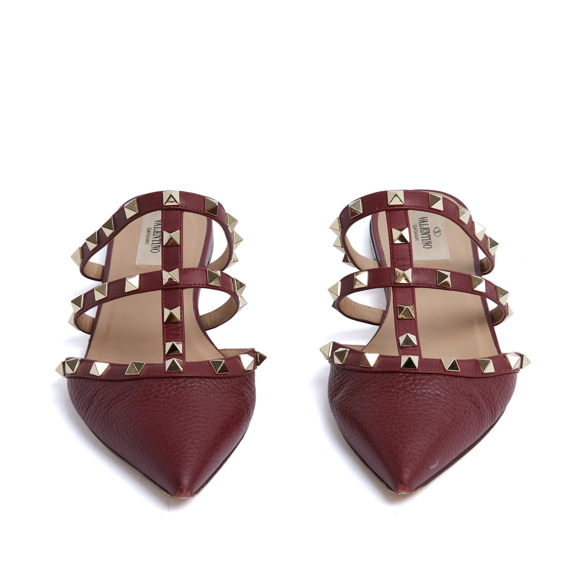 Valentino shoes Rockstud series mules in dark red almost burgundy grained leather decorated with gold metal studs on 2 thin straps and the front of the foot, pointed toe, leather lining and inner and outer soles. Size 38.5EU: heel 0.5 cm, insole