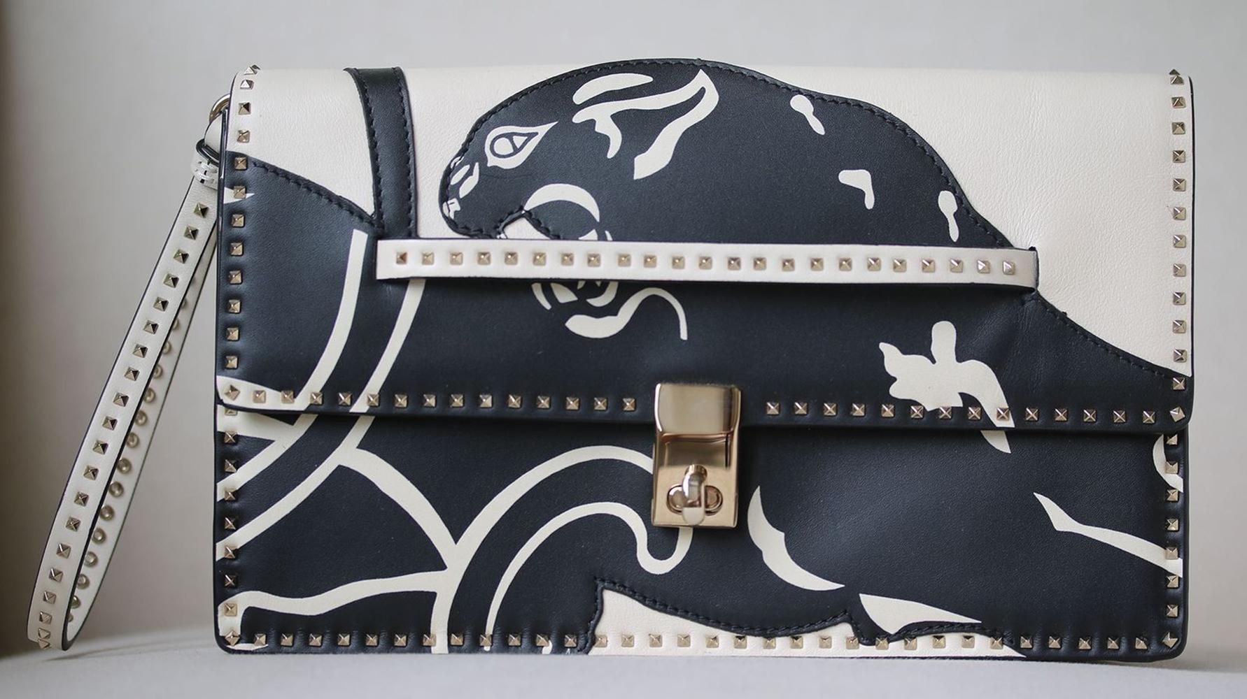 Bring signature appeal to your ensemble with this cream leather Valentino Garavani panther clutch from Valentino, featuring contrasting panels, a hand strap, foldover top with twist-lock closure and micro gold-tone Rockstuds. Material: Calf
