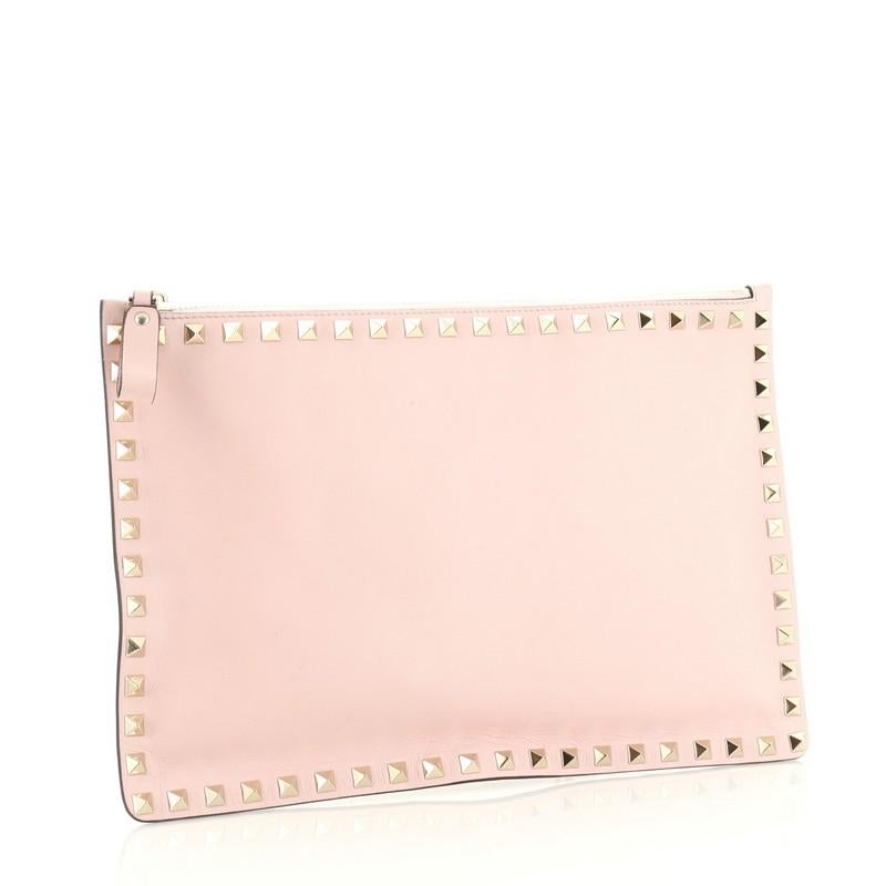 This Valentino Rockstud Pouch Leather Large, crafted from pink leather, features rockstud detailing and gold-tone hardware. Its zip closure opens to a pink fabric interior. 

Estimated Retail Price: $1,395
Condition: Very good. Creasing, scuffs and