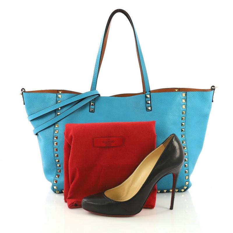 This Valentino Rockstud Reversible Convertible Tote Leather Medium, crafted from blue leather, features pyramid rockstud detailing, dual tall flat handles, and gold-tone hardware. It opens to a reversible brown leather interior. **Note: Shoe