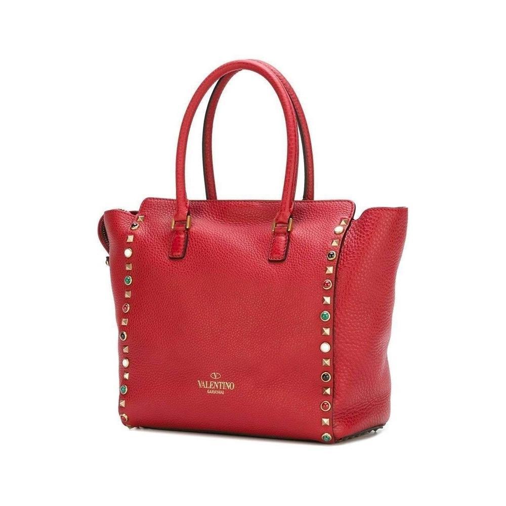 Red calf leather 'Rockstud Rolling' trapeze tote from Valentino featuring round top handles, a flip-lock closure, gold-tone Rockstud embellishments, a top zip fastening, an internal zipped pocket, 
an internal logo patch, a detachable shoulder strap