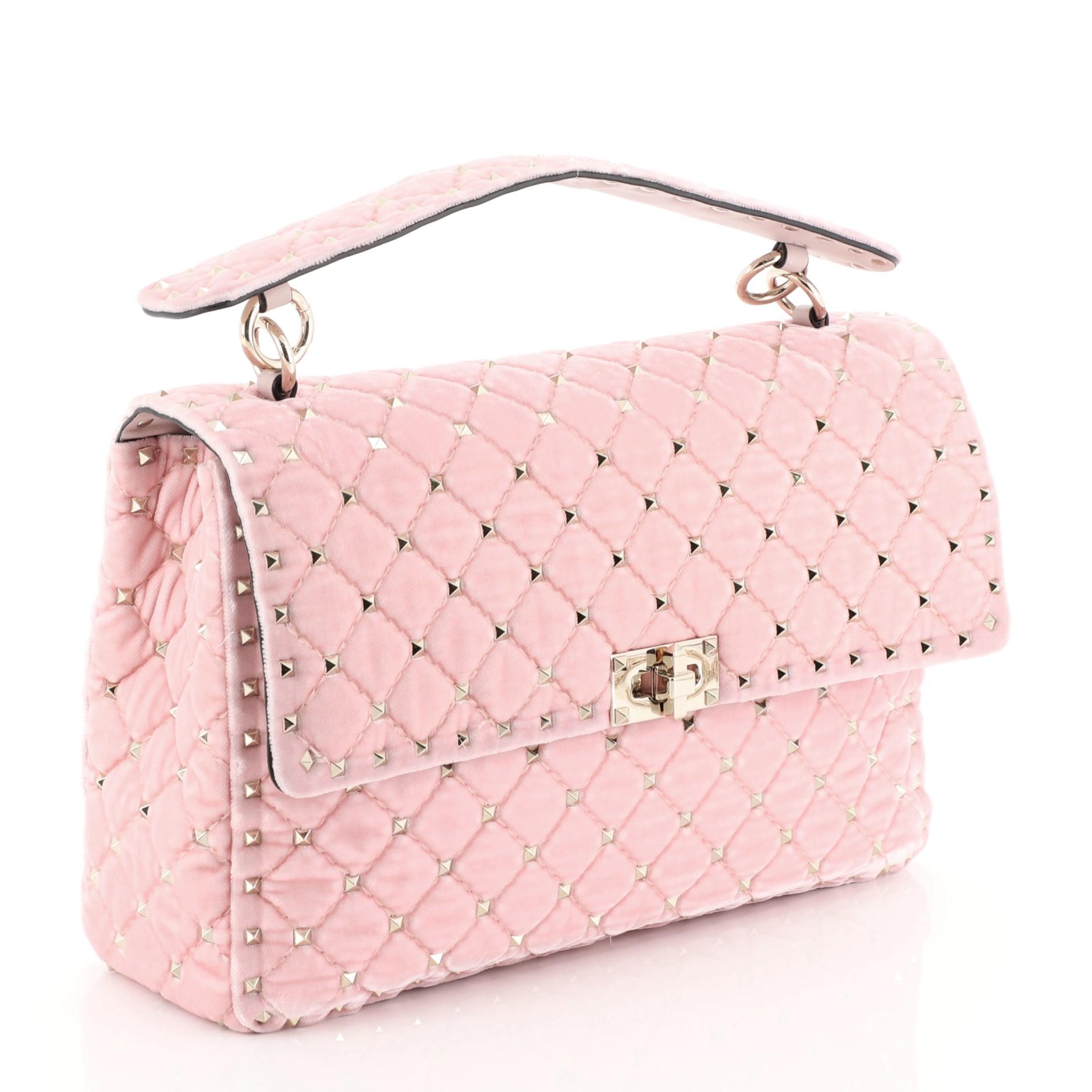 This Valentino Rockstud Spike Flap Shoulder Bag Quilted Velvet Large, crafted from pink quilted velvet, features pyramid stud embellishments, leather handle with stud detailing, chain-link strap, and silver and white-tone hardware. Its turn-lock