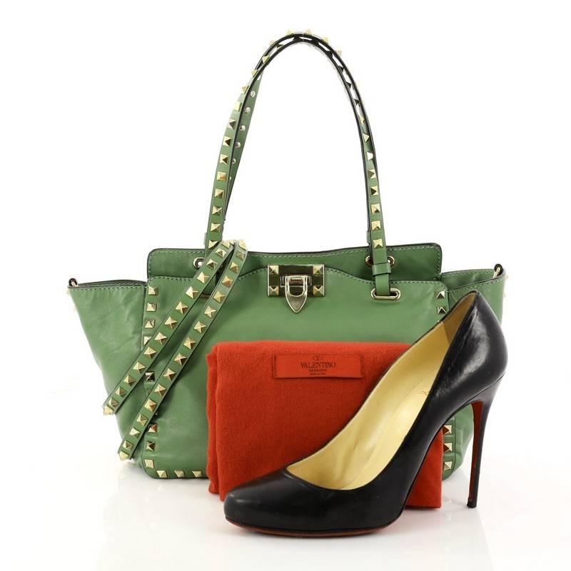 This authentic Valentino Rockstud Tote Soft Leather Small mixes edgy style with luxurious detailing. Crafted from green leather, this stylish tote features dual tall flat handles, gold-tone pyramid stud trim details, a signature clasp fastening,