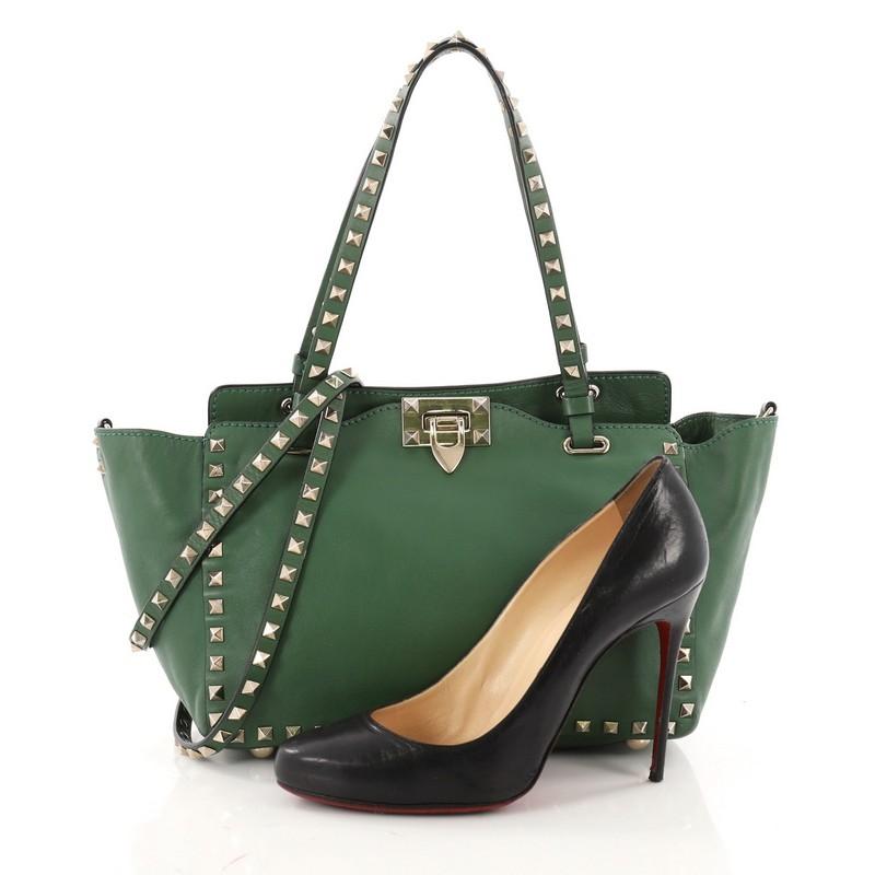 This authentic Valentino Rockstud Tote Soft Leather Small mixes edgy style with luxurious detailing. Crafted from green soft leather, this stylish tote features dual tall flat handles, gold-tone pyramid stud trim details, signature clasp lock, stamp