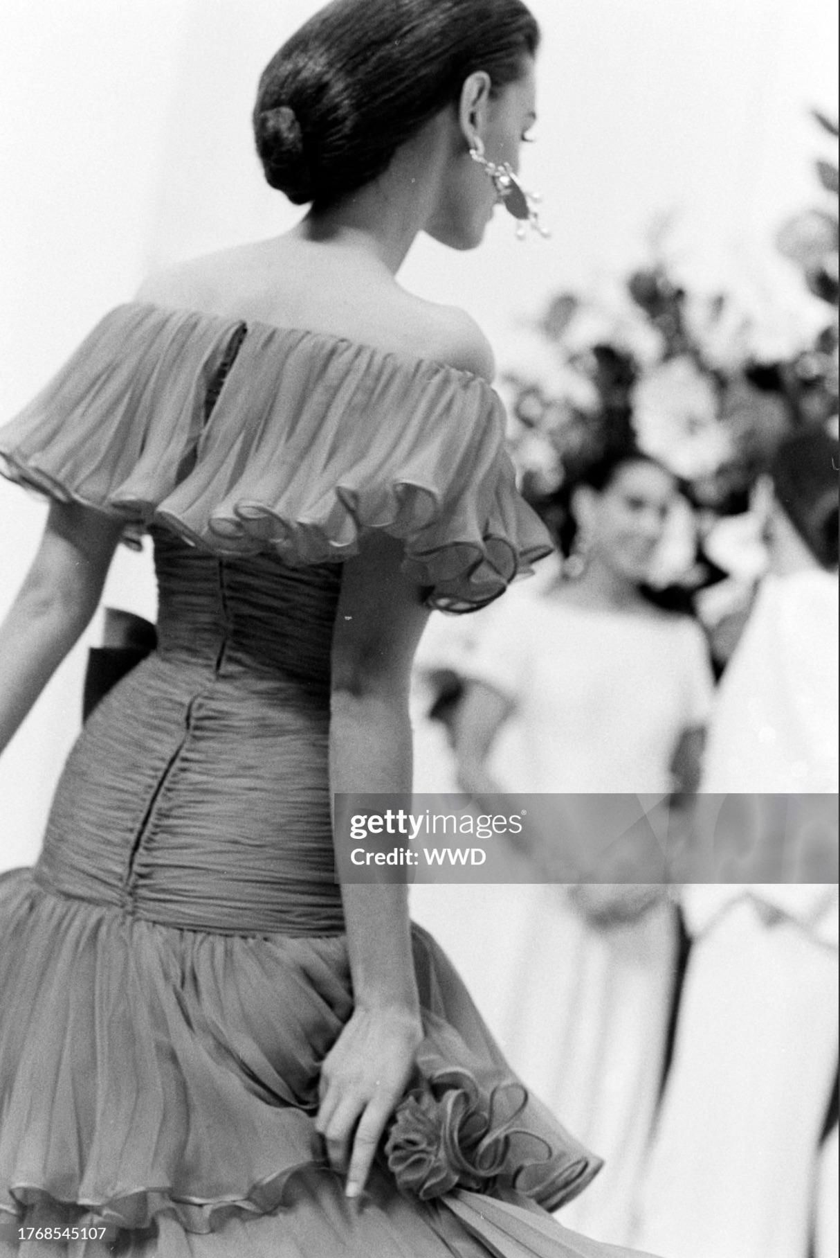 La collezione di Valentino per la primavera del 1990 è stata caratterizzata da una miriade di volant favolosi. Delicati e femminili, i volant e le ruche in chiffon di seta micro-pieghettato decorano ed elevano la silhouette di questo abito di