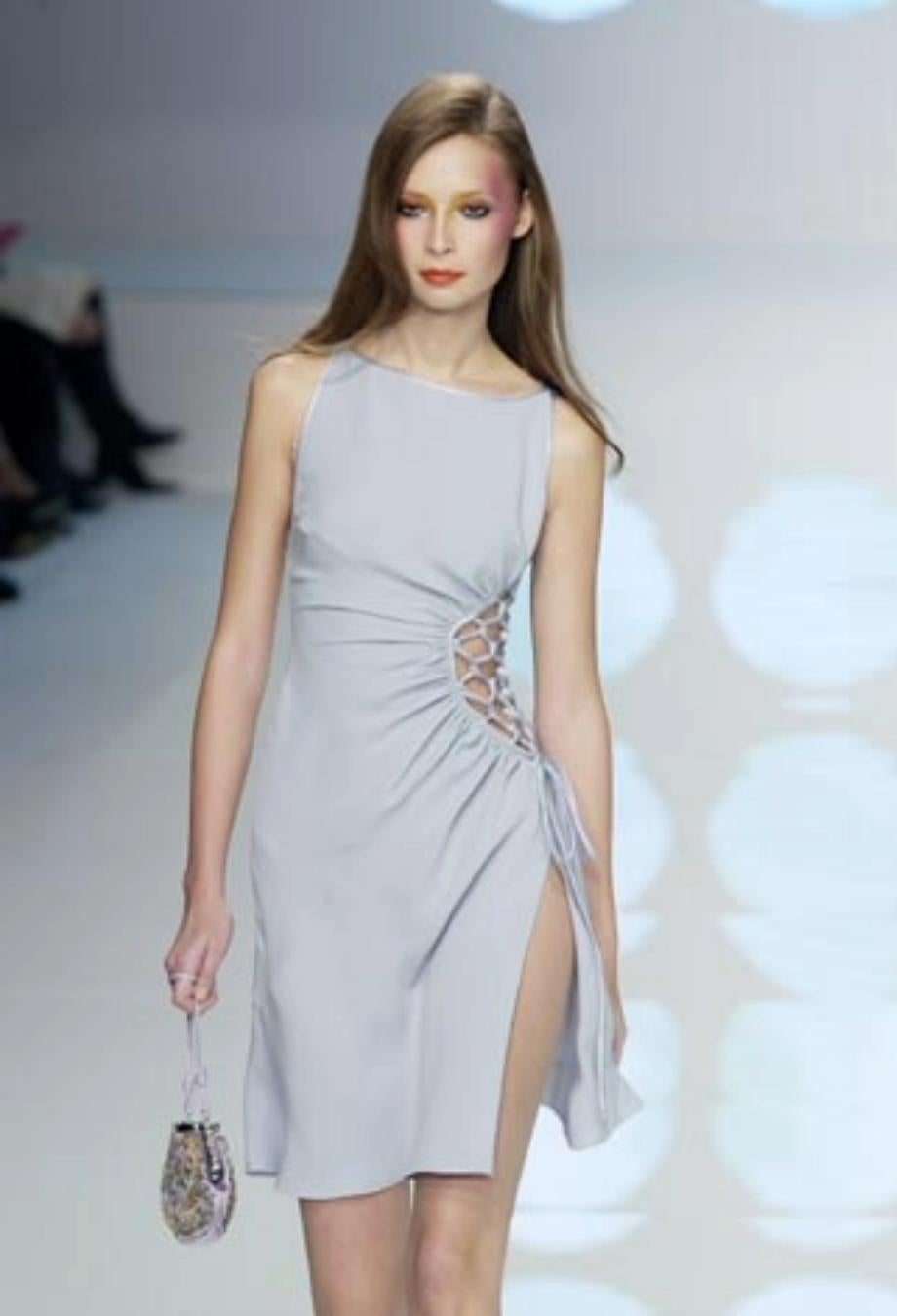 This Valentino Spring/Summer 2004 runway dress in powder blue is cut from lustrous silk, with the silhouette draping gracefully across the body with asymmetric ruching that gathers into a latticework detail along the side. The open side is threaded