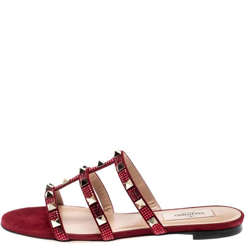 These Valentino slides feature a stunning scarlet suede body that comes with straps on the top and detailed with the signature Rockstuds. Easy to slide it on and off, these pair makes a great accompaniment to dresses and skirts alike. Style with a