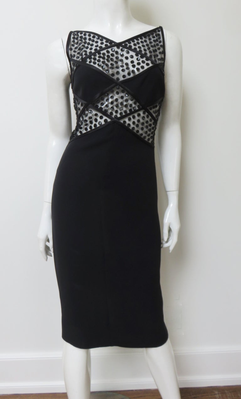 An incredible black silk dress by Valentino.  It is sleeveless, semi fitted with a solid silk skirt and diamond shaped panels over the bustline. There are angular bead enhansed black silk lace panels above and below the bust and at the waist of the