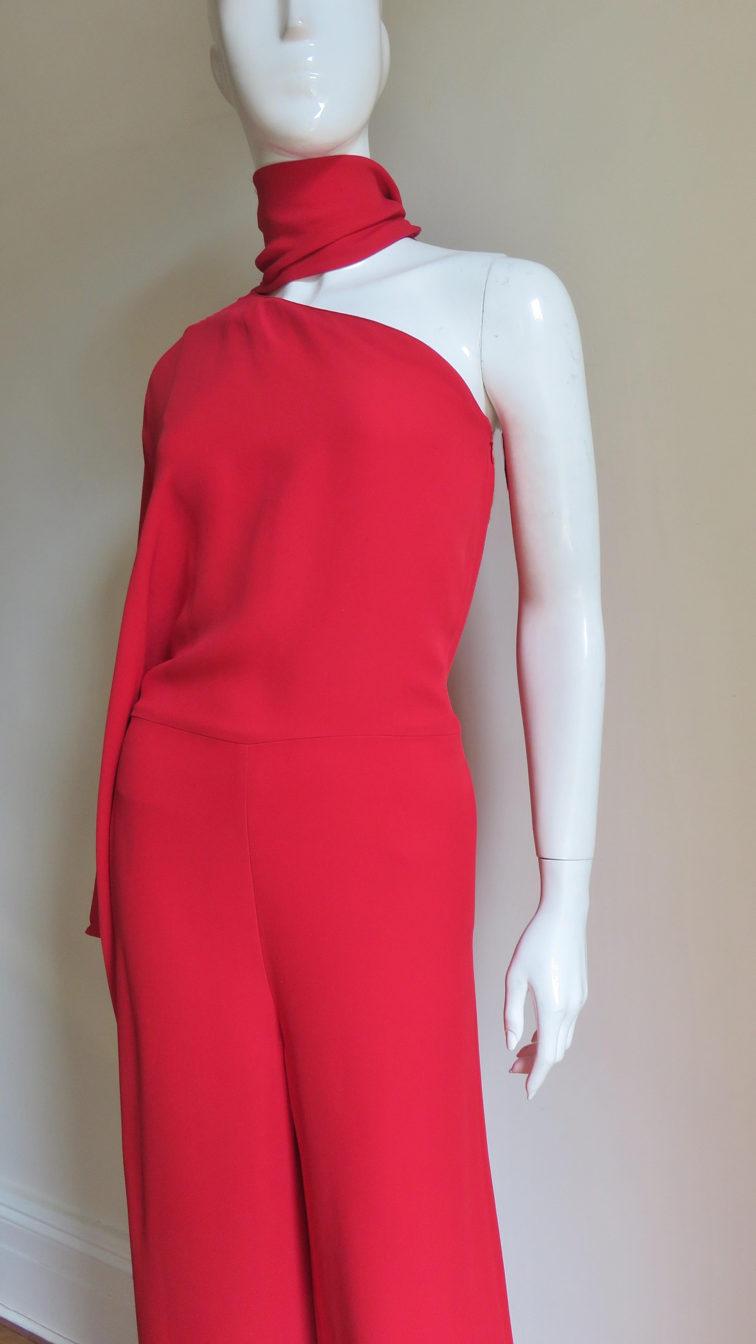 An incredible red silk jumpsuit from Valentino.  It has one kimono sleeve, a tie at the neck which can be worn a number of ways and wide pant legs. The jumpsuit has an invisible side zipper, side seam pockets at the hips, and the top portion is