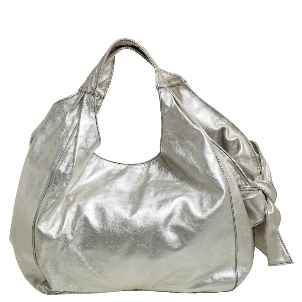 The signature Valentino bow on the side is the highlight of this Nuage Bow hobo. It is crafted using silver leather and equipped with two handles and a spacious canvas interior. This eye-catching bag will add a chic finish to your favorite looks.


