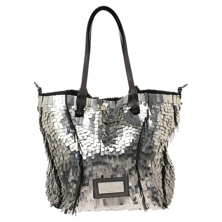 Celebrating luxury and femininity through its signature designs, Valentino brings this lovely tote that is sure to elevate your style game. The bag exudes opulence, boasting an array of attractive embellishments and a spacious satin interior. This