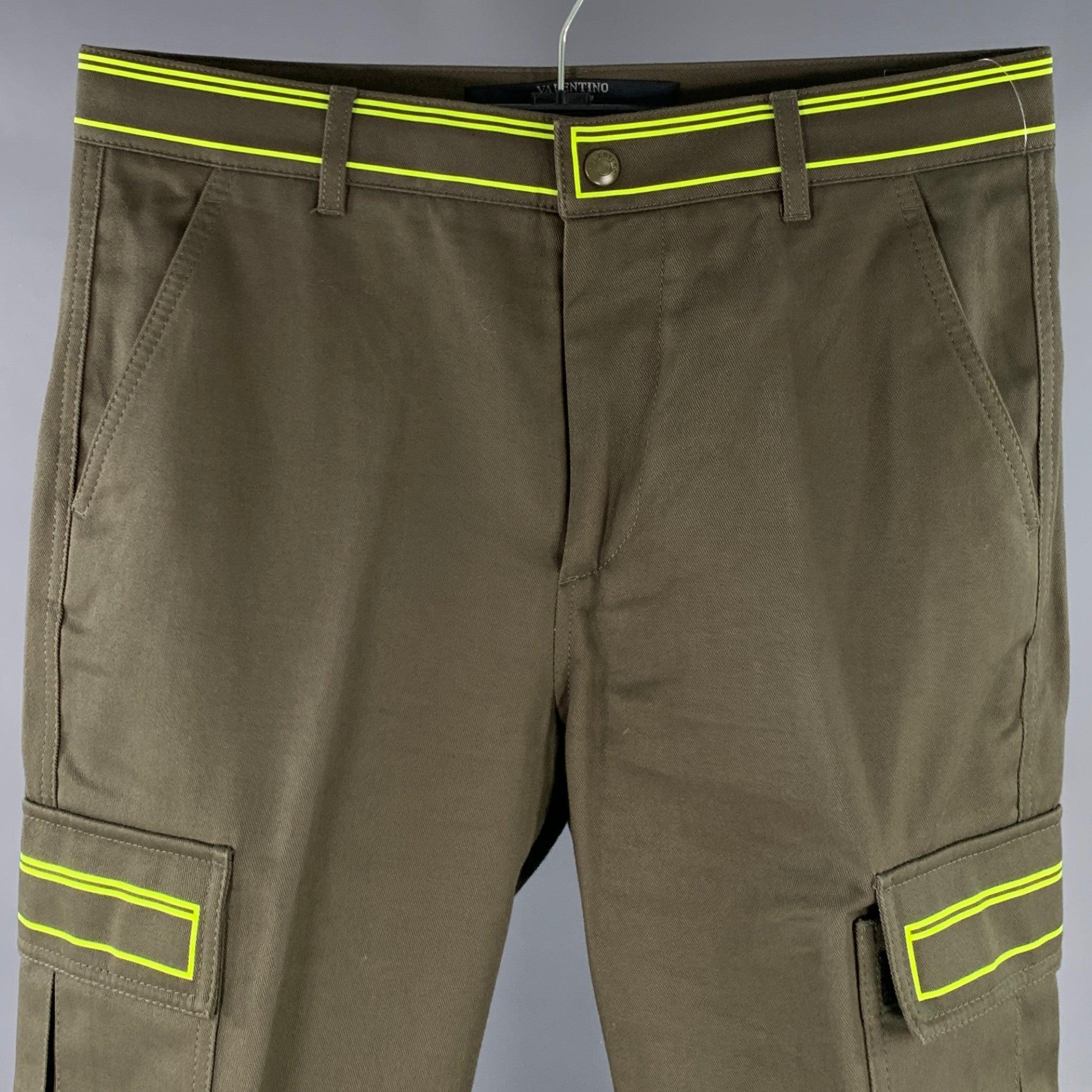 Pantalon décontracté Valentino
en sergé de coton vert olive, avec un style cargo et de multiples grandes poches, une ceinture et des garnitures de poche vert fluo, et une fermeture à glissière. Fabriqué en Italie. Très bon état.
 Marques mineures.