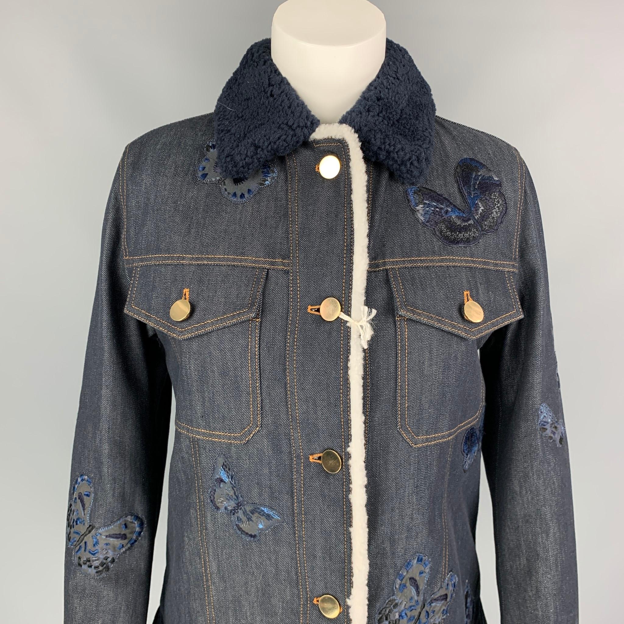 VALENTINO jacket comes in a navy cotton with a embroidered butterfly details featuring a shearling liner, shearling collar, side slits, contrast stitching, gold tone hardware, flap pockets, and a buttoned closure. Made in Italy. 

New With Tags.