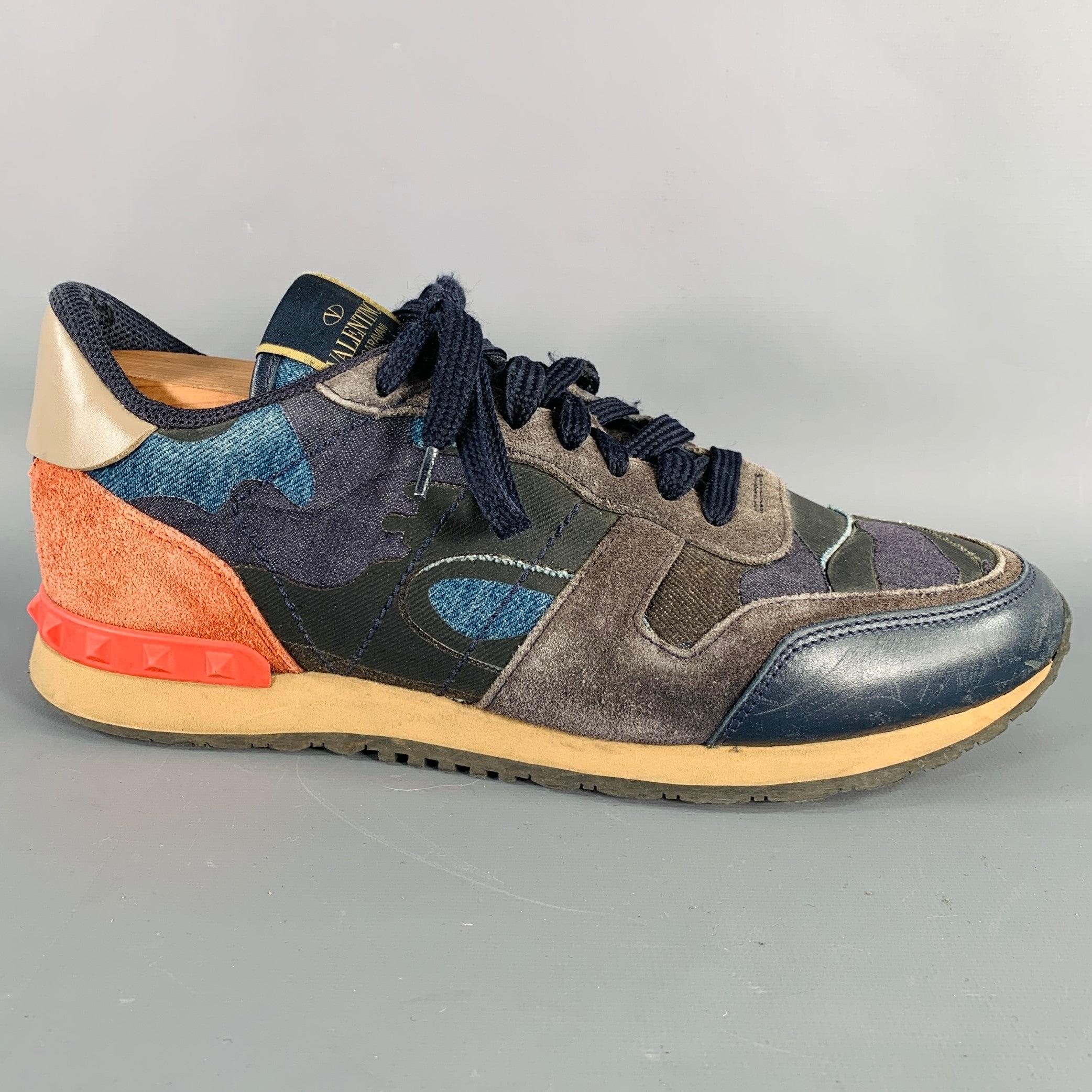 VALENTINO sneakers in a black, blue, and red suede and leather featuring a color block style, rubber Rockstud heel details, and lace-up closure. Shoe trees not included. Made in Italy.Good Pre-Owned Condition. Moderate signs of wear, as is.