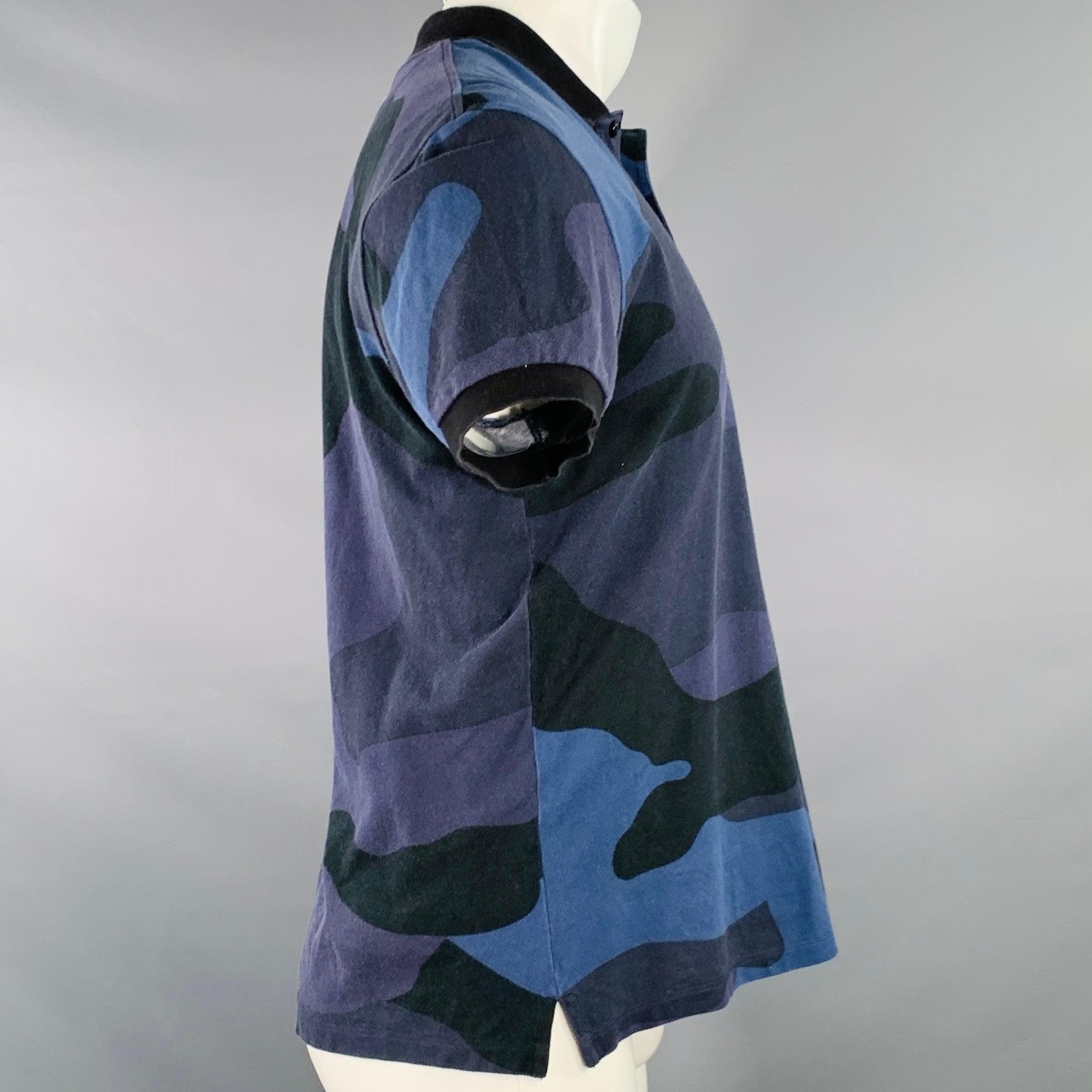Polo VALENTINO
en piqué de coton noir et bleu, avec un motif camouflage et une demi-patte de boutonnage. Fabriqué en Italie. Excellent état.  

Marqué :   M 

Mesures : 
 
Épaule : 19 pouces Poitrine : 42 pouces Manches : 7.5 pouces Longueur : 25