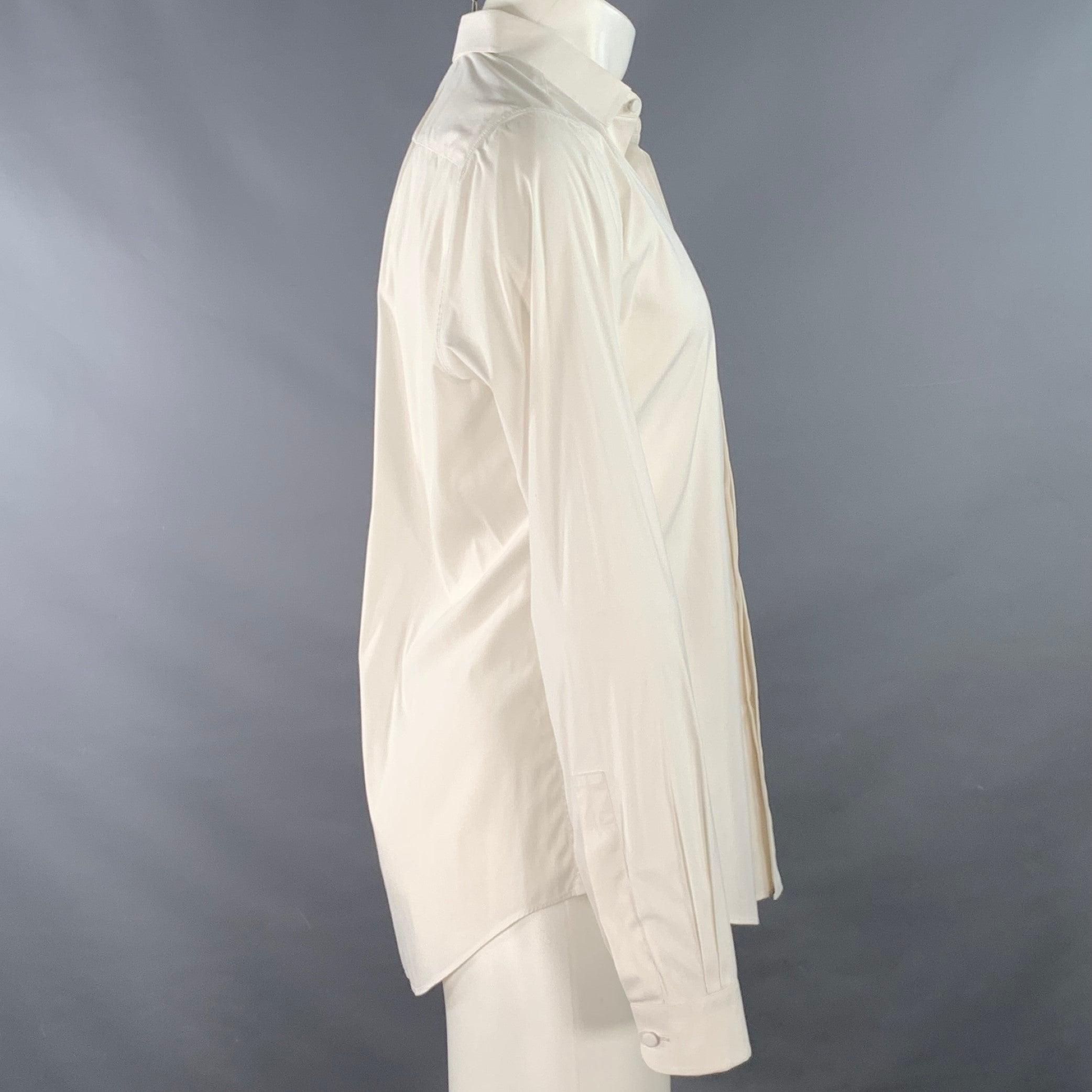 Chemise VALENTINO à manches longues en tissu de coton blanc, avec un col rond, des poignets arrondis à bouton unique et une fermeture à bouton caché. Fabriqué en Italie. Très bon état. Petite marque difficile à voir sur la manchette. 

Marqué :  