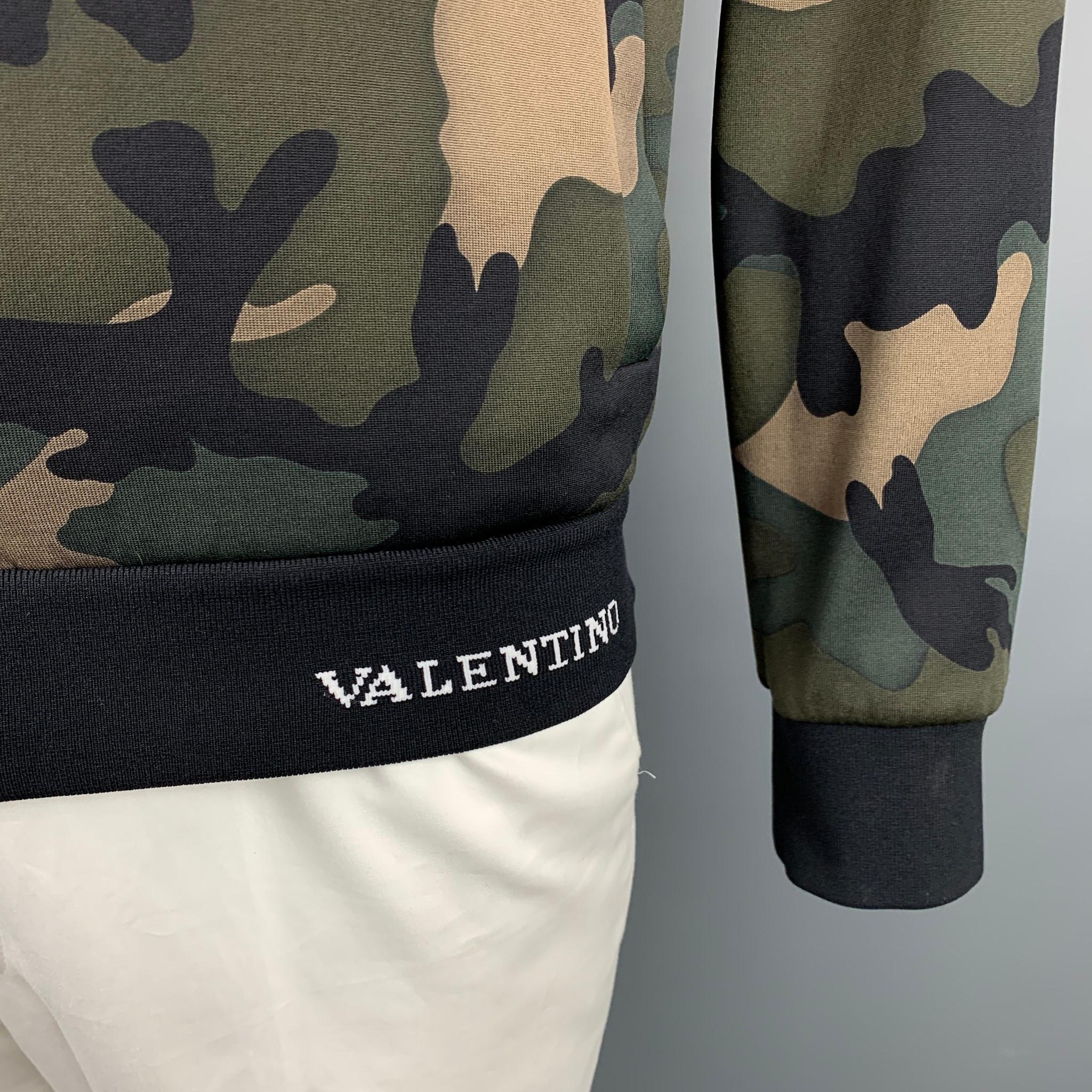 VALENTINO sweatshirt comes in a olive & black camouflage polyamide featuring a high collar, small logo detail, slit pockets, and a full zip up closure. Stripe on sleeve removed. Made in Italy.

Very Good Pre-Owned Condition.
Marked: XL
Original