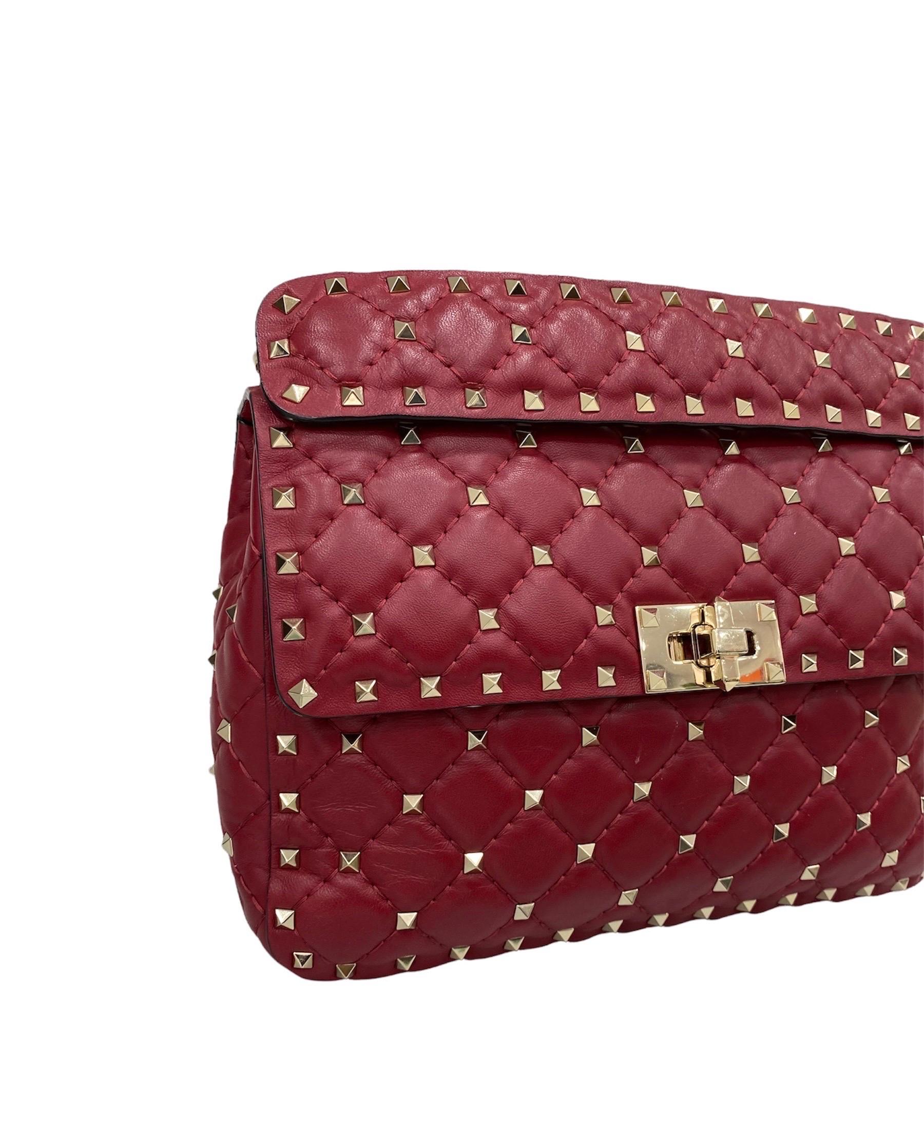 Valentino bag, Spike model, Rockstud line, made of red leather with golden studs and hardware.

Equipped with an interlocking closure, internally lined in red leather, quite roomy.

Equipped with a removable central handle and a removable chain