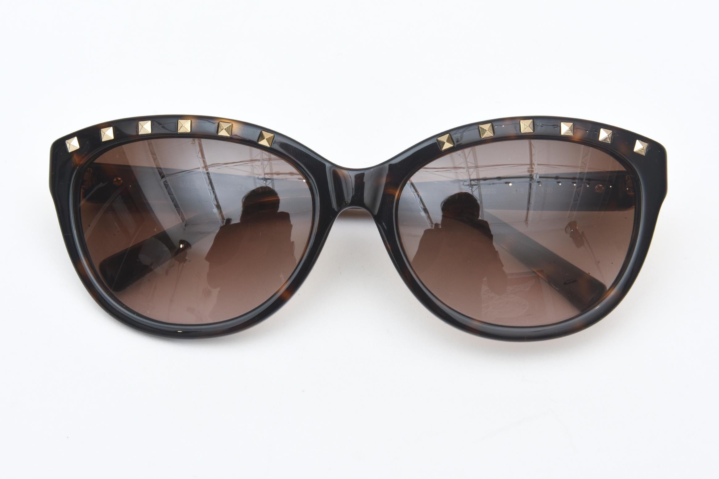 Cette ravissante paire de lunettes de soleil Valentino à clous en laiton est en forme d'œil de chat. Toujours flatteur pour le visage. La couleur est marron effet tortue. Comme nous l'avons dit, ils ont des goujons sur le cadre. Ils n'ont jamais été
