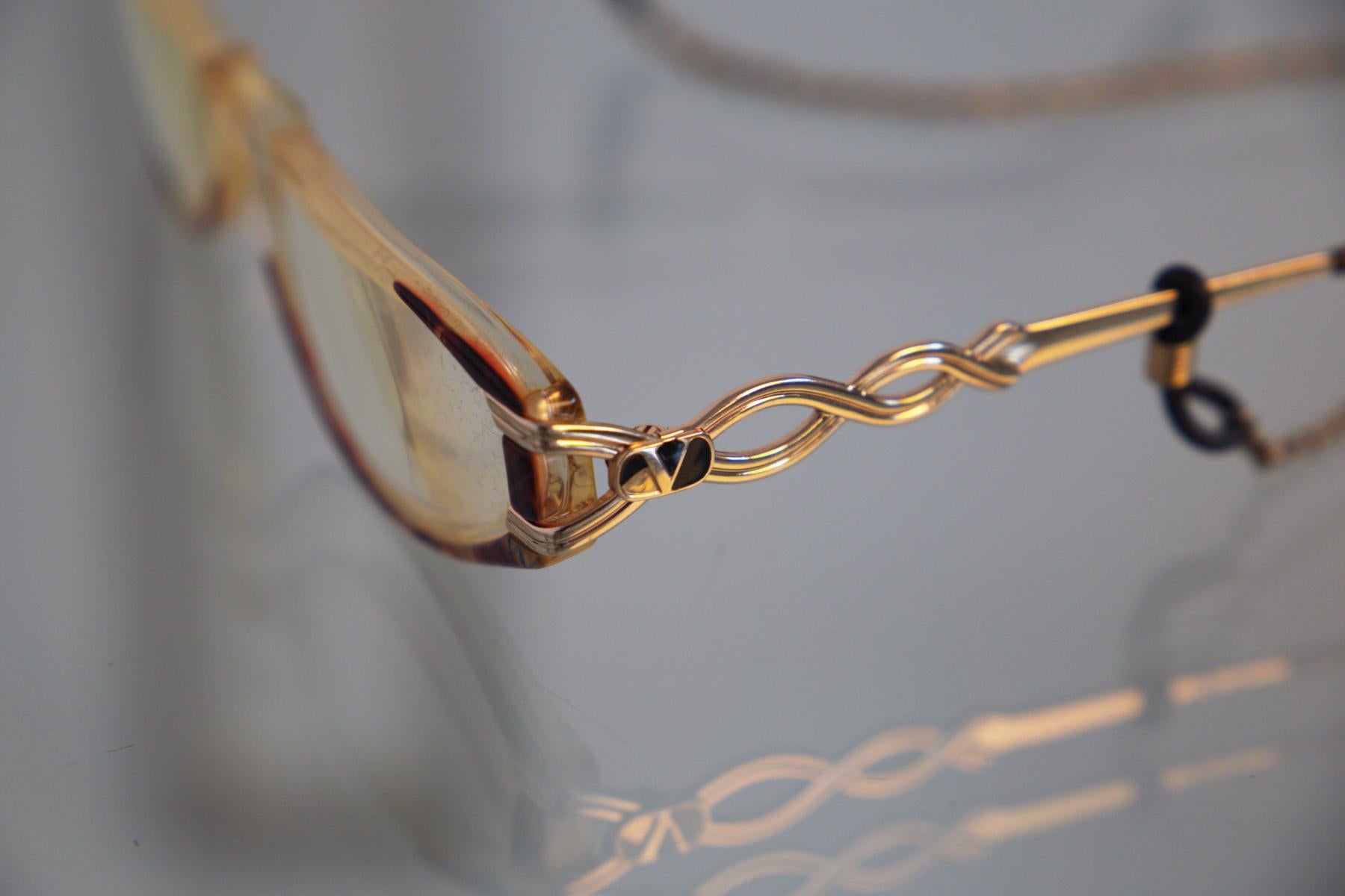 Gorgeous, elegant prescription glasses designed by Valentino in the 1990s, made in Italy. ORIGINAL BRAND.
The frame is very sweet and cat-eye, tortoiseshell style. The wands are shiny gold in a very nice woven pattern with Valentino's signature on