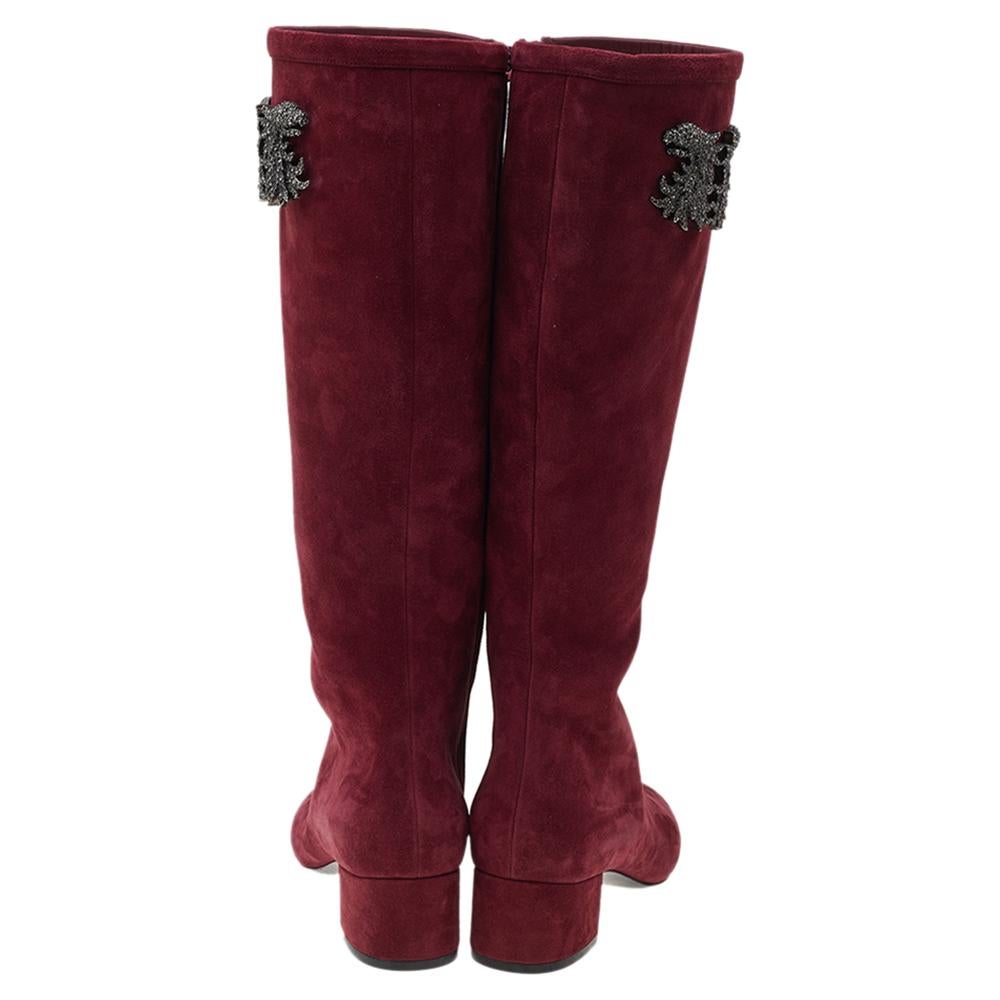 Valentino never fails to design fashion-forward styles that become favorites in one's closet. These burgundy knee-length boots for women are a fine example. Made from suede, they feature round toes, embellished motifs, and block heels.

Includes: